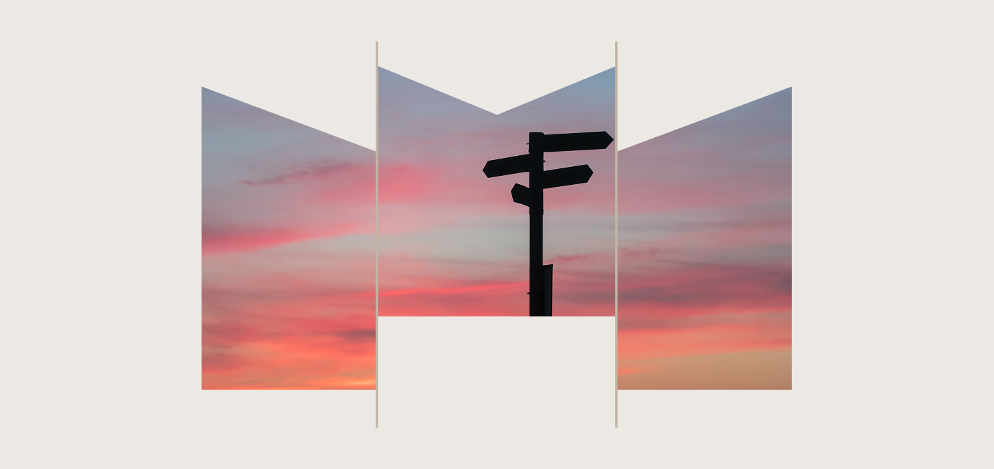Silhouette of a multi-directional street sign in front of a pink sky at sunrise.