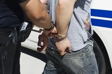 The image depicts a police officer arresting a suspect and placing them in handcuffs.