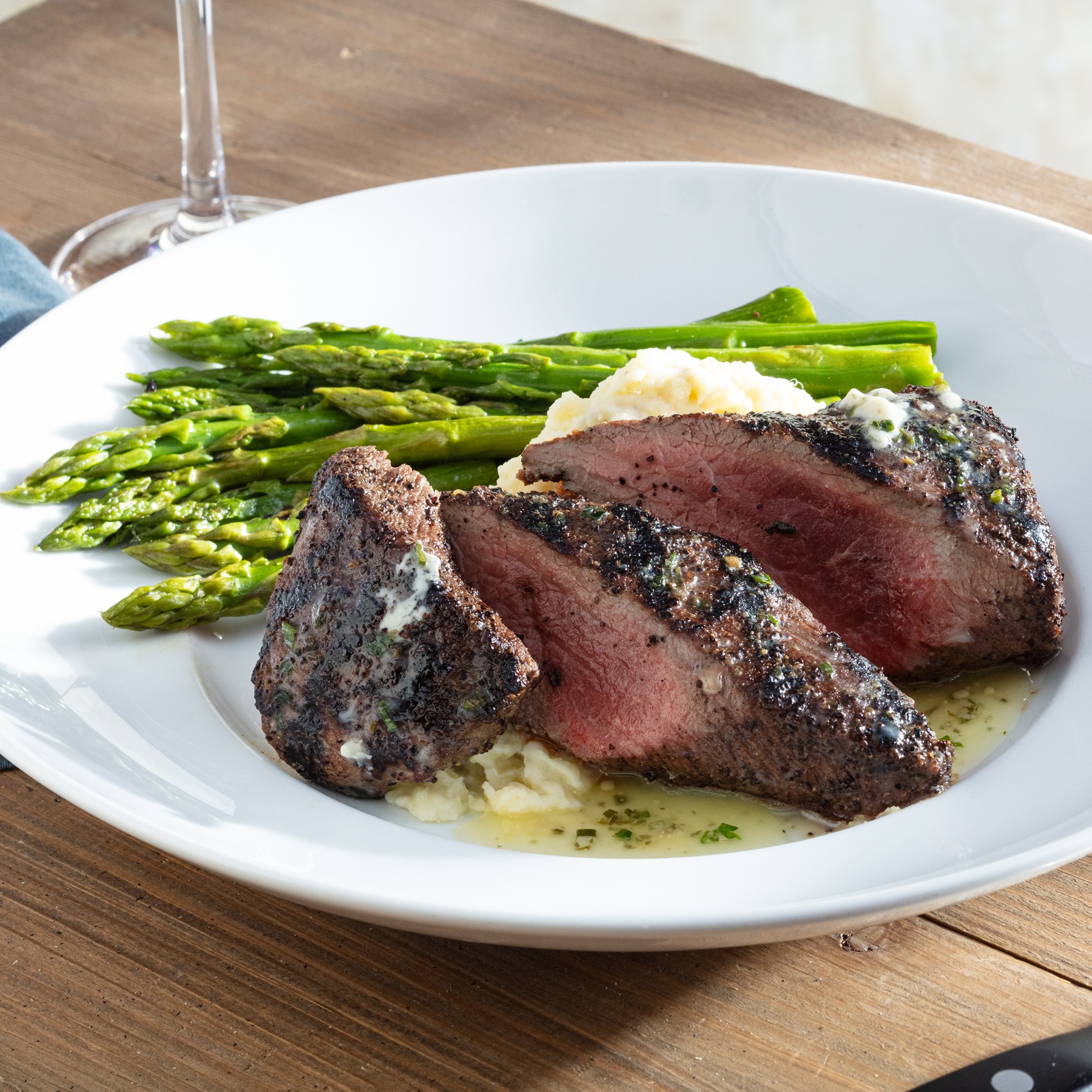 Wood-Grilled Kona-Crusted Lamb Loin served with asparagus, Yukon mash and herb butter.