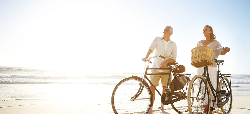 A couple riding their bikes together in the sun.