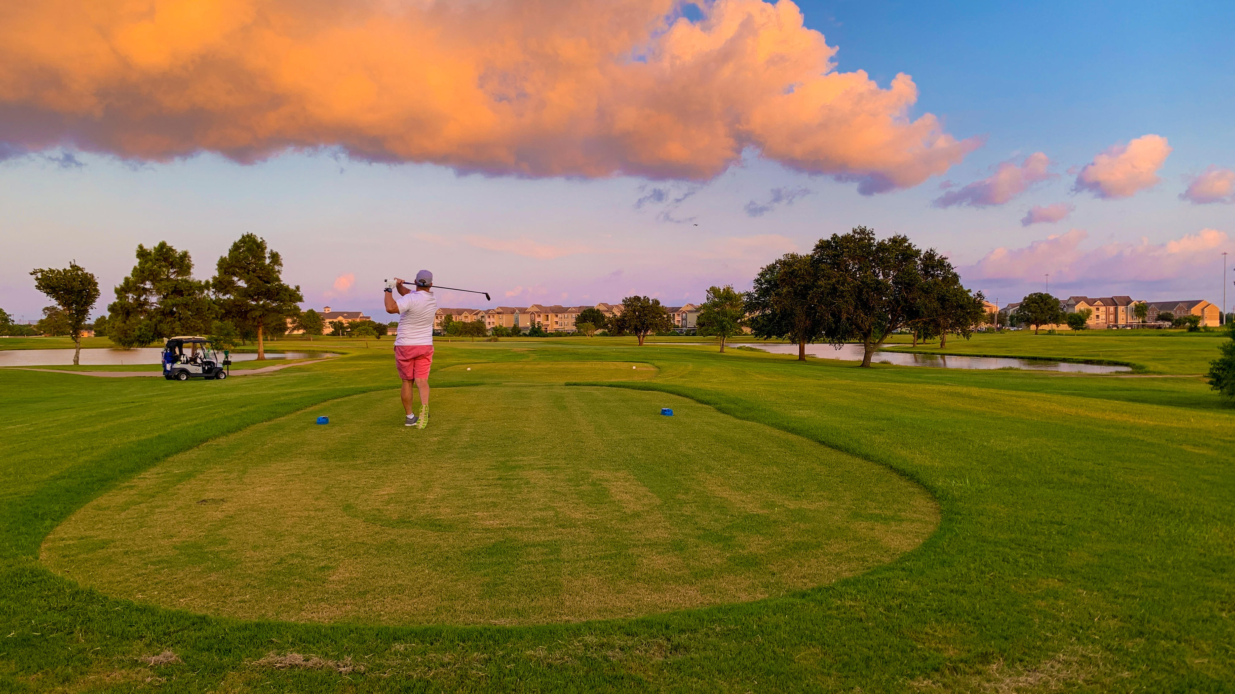 man swings a golf club at sunset at the Babe Zaharias golf course in Port Arthur, Texas