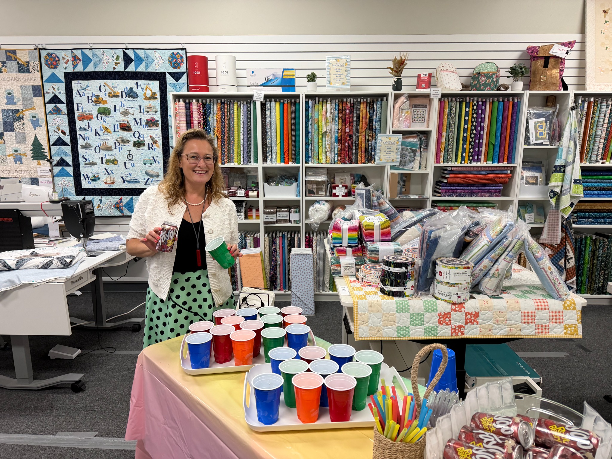 A welcoming refreshment table greets guests during a Decorative Stitch quilting class, surrounded by colorful fabric collections and quilting supplies. A fun event celebrating creativity, learning, and community.