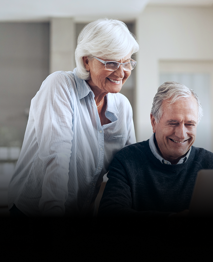 An elderly couple reviewing their accounts on their laptop.