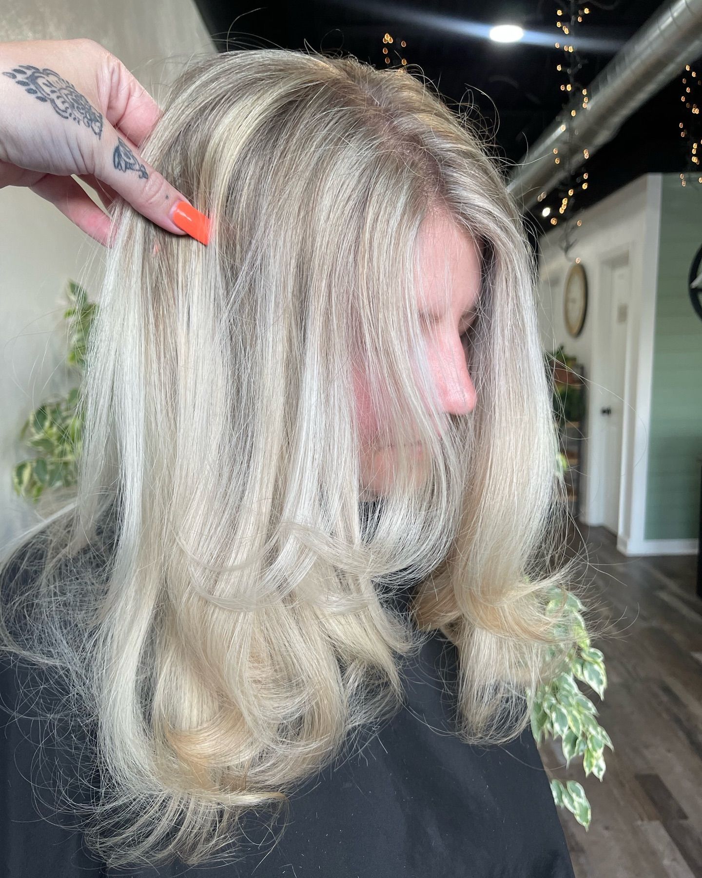 Side view of light blonde layered hair styled with soft curls, showcasing smooth texture and bright salon-finished color.