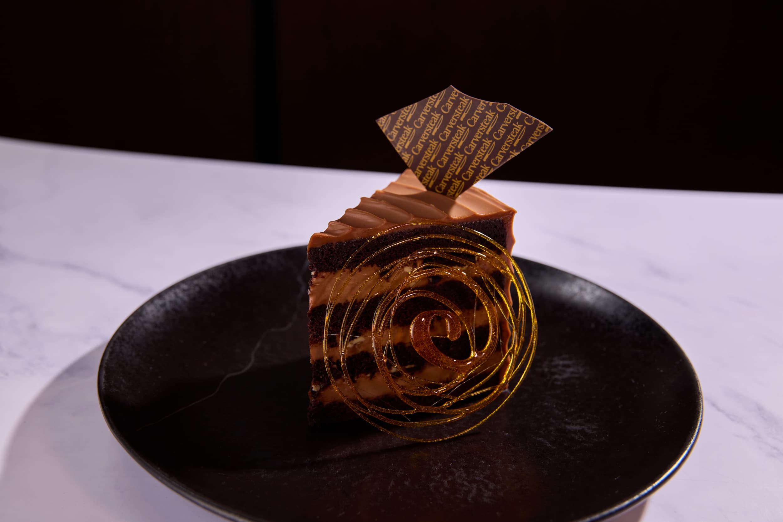 Decadent chocolate layer cake with gold sugar garnish at Carversteak NYC.