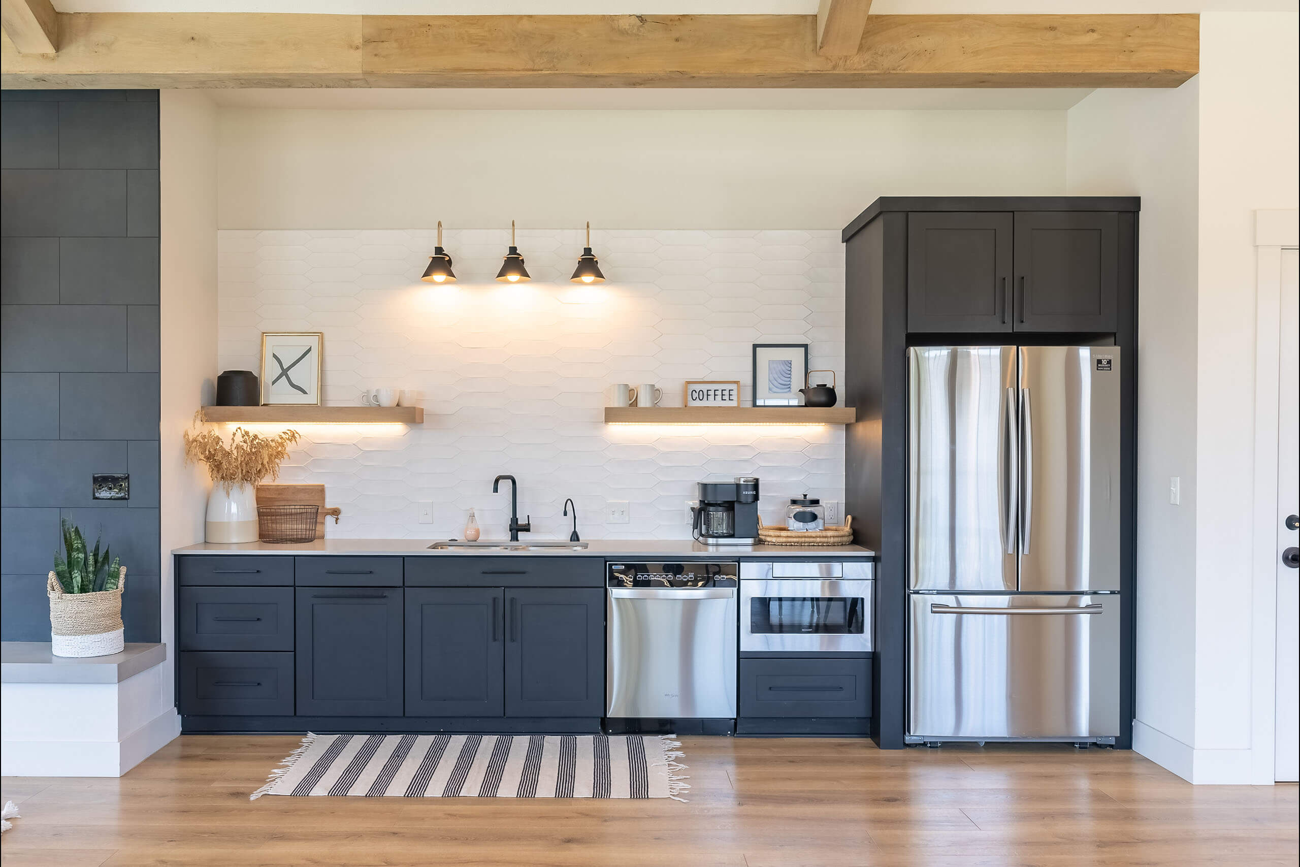 A kitchen with a black fridge and a white sink.
