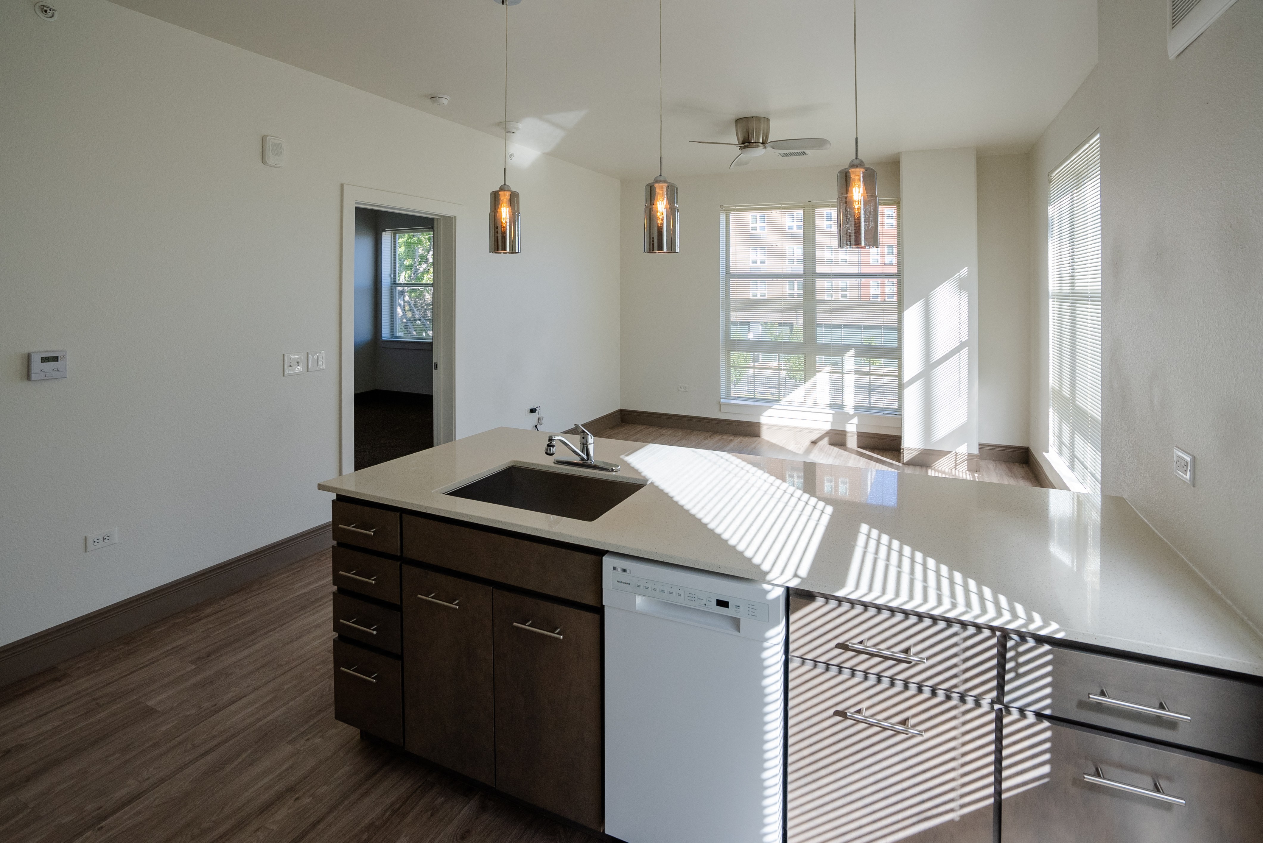 A modern kitchen with a white countertop and wooden cabinets.