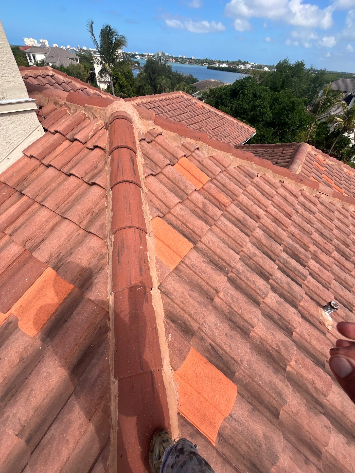 View across a terracotta tile roof on a Florida home, showing the roof slope, tile pattern, and surr 