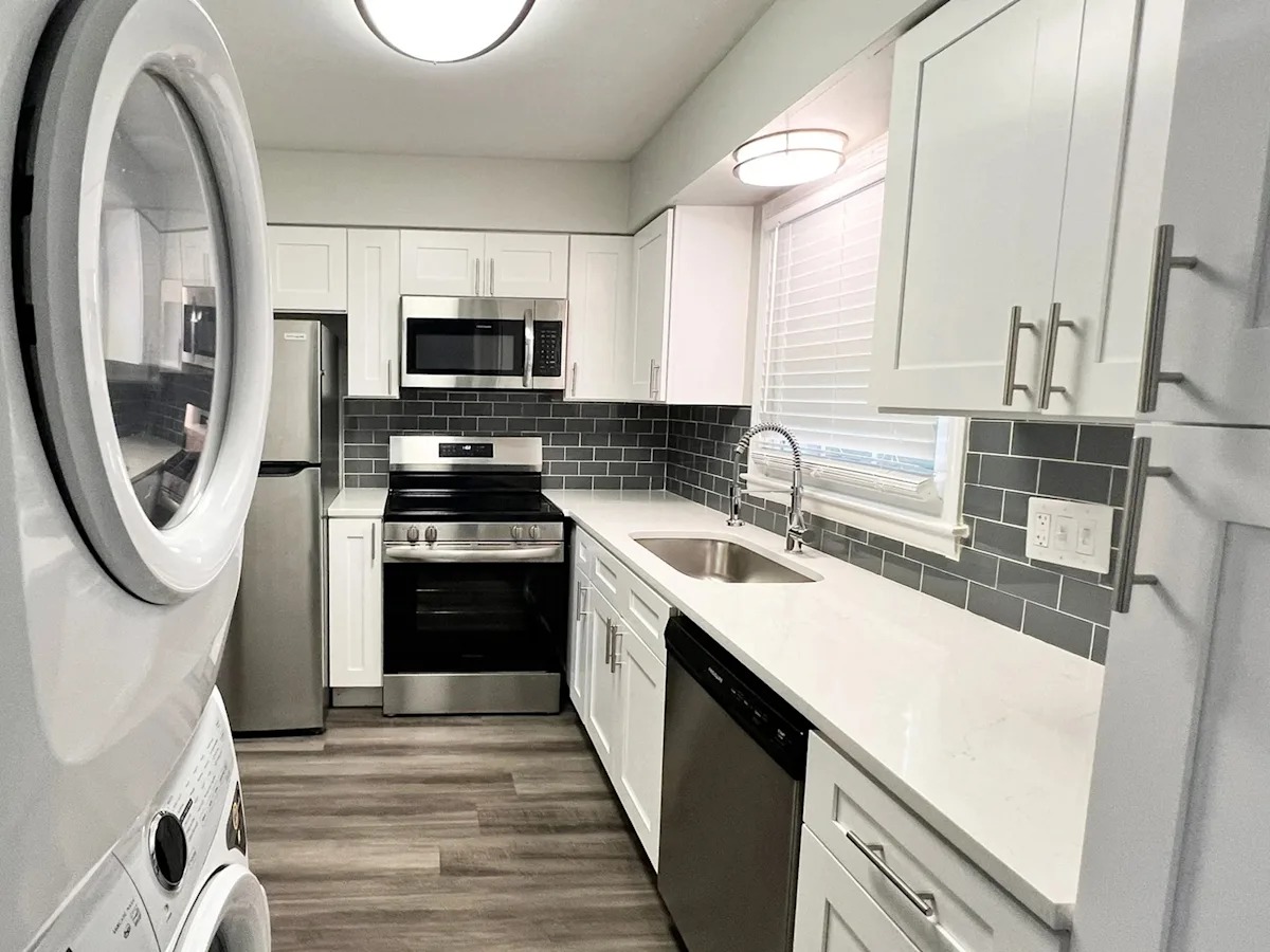 A modern kitchen with white cabinets and a black backsplash