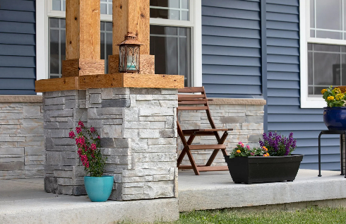 Exterior entry curb appeal featuring stacked grey stone veneer porch columns, natural cedar timber p 