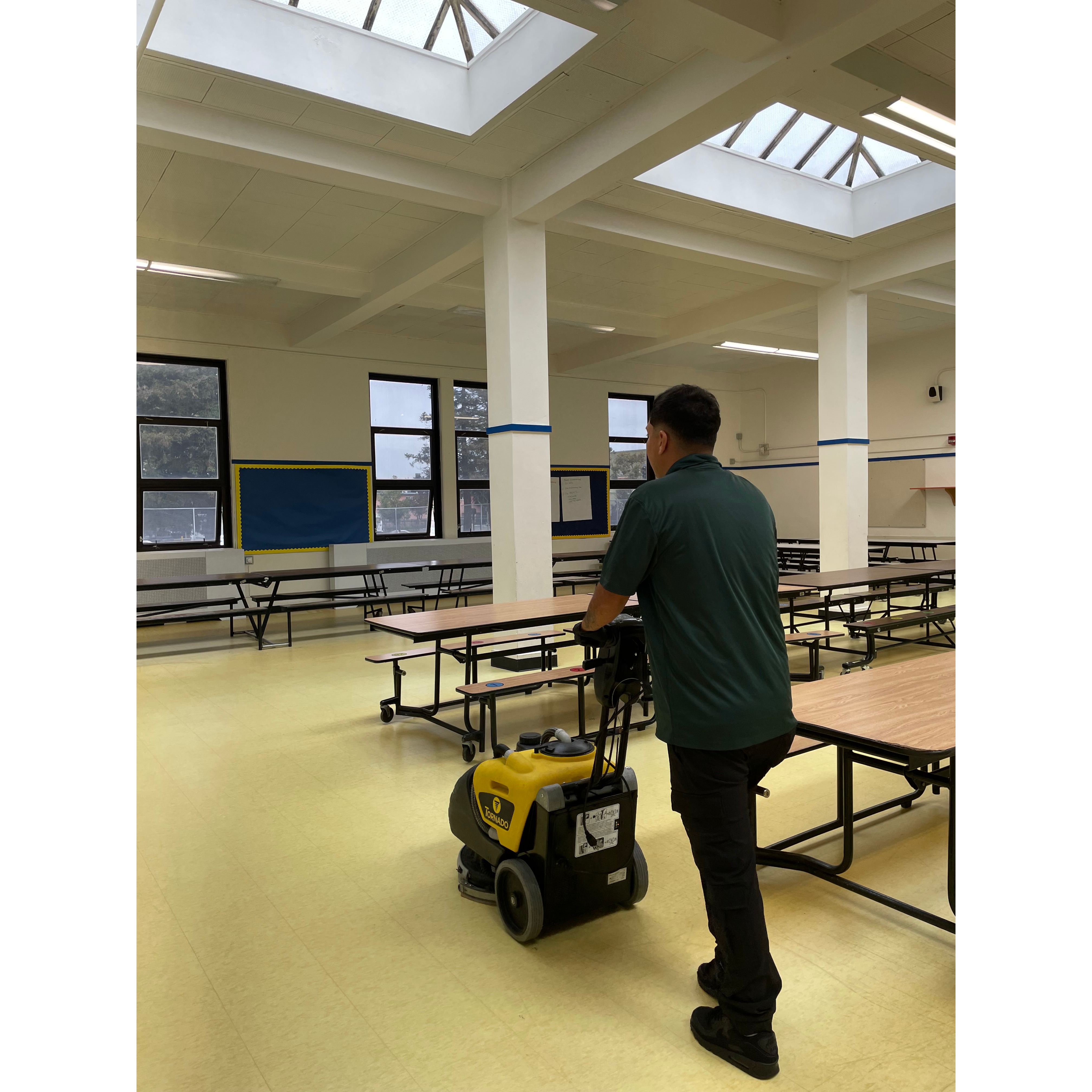 A Star's Janitorial Services team member mopping the floor of a large cafeteria and dining hall as part of facility cleaning in the Concord, CA area.