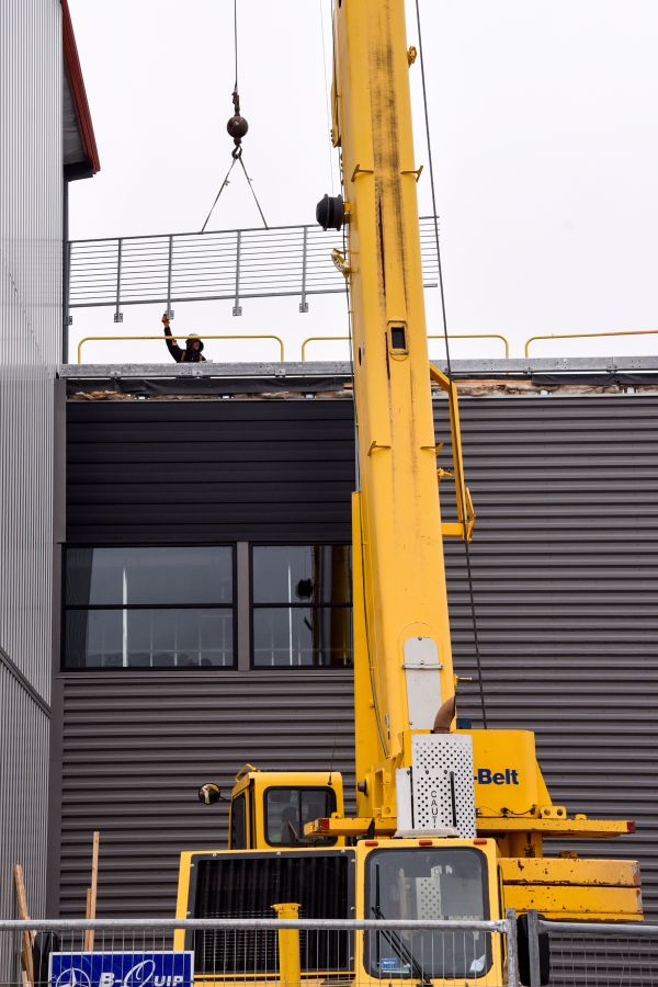 Crane from American Aerial Services safely lifting and placing structural steel in Portland, Maine, showcasing expert crane and rigging services.