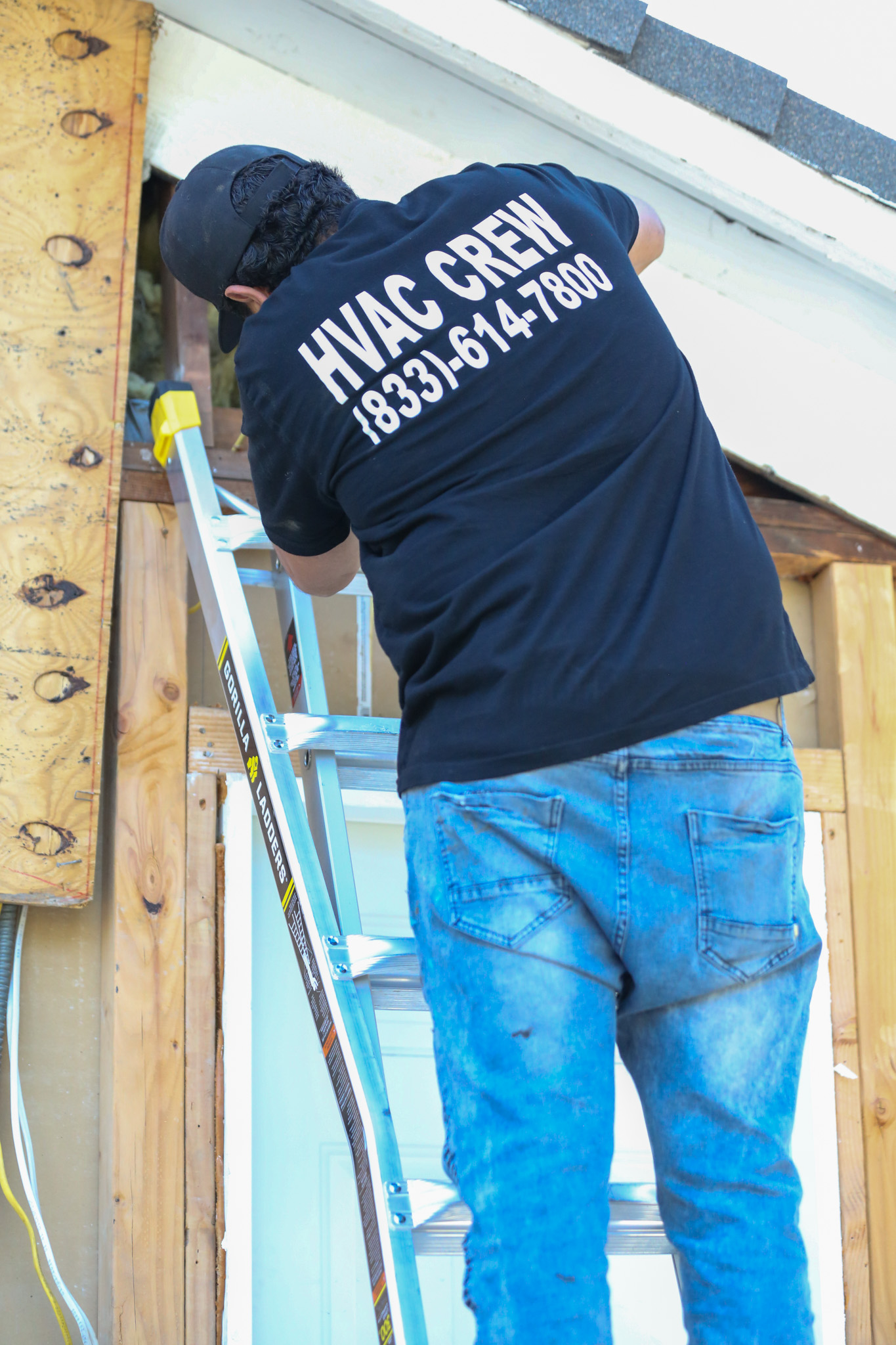 An Affordable Heating and Air crew member works from a ladder on a residential HVAC installation, handling ductwork and structural access at a Ventura County home.