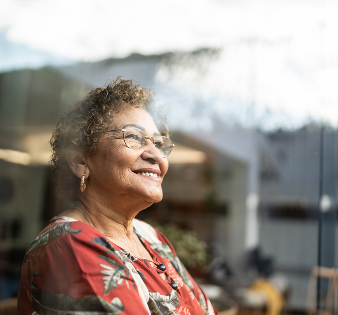 A woman smiling, as seen through a window.