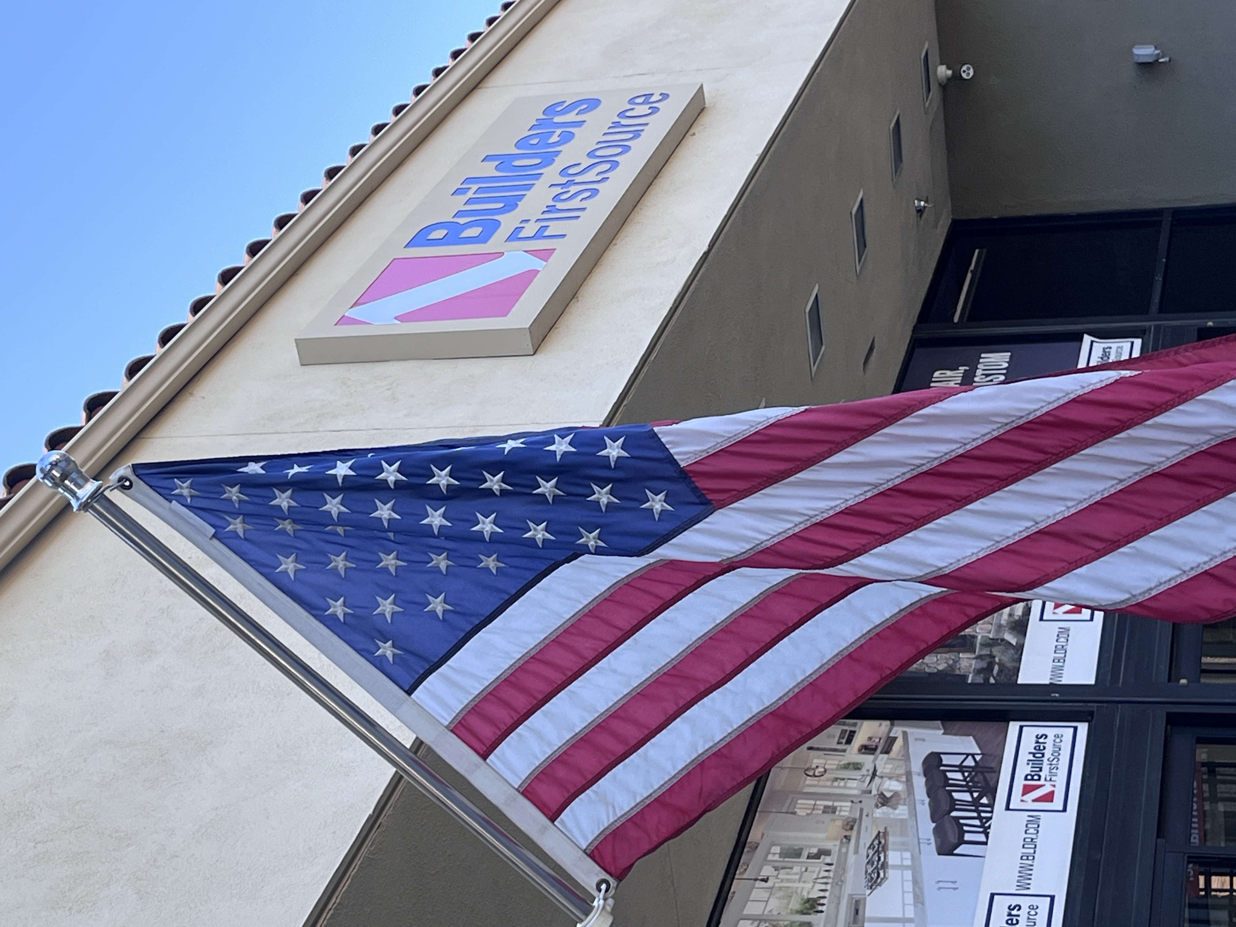Close-up of the Builders FirstSource sign and American flag at the Thousand Oaks, CA storefront entrance.