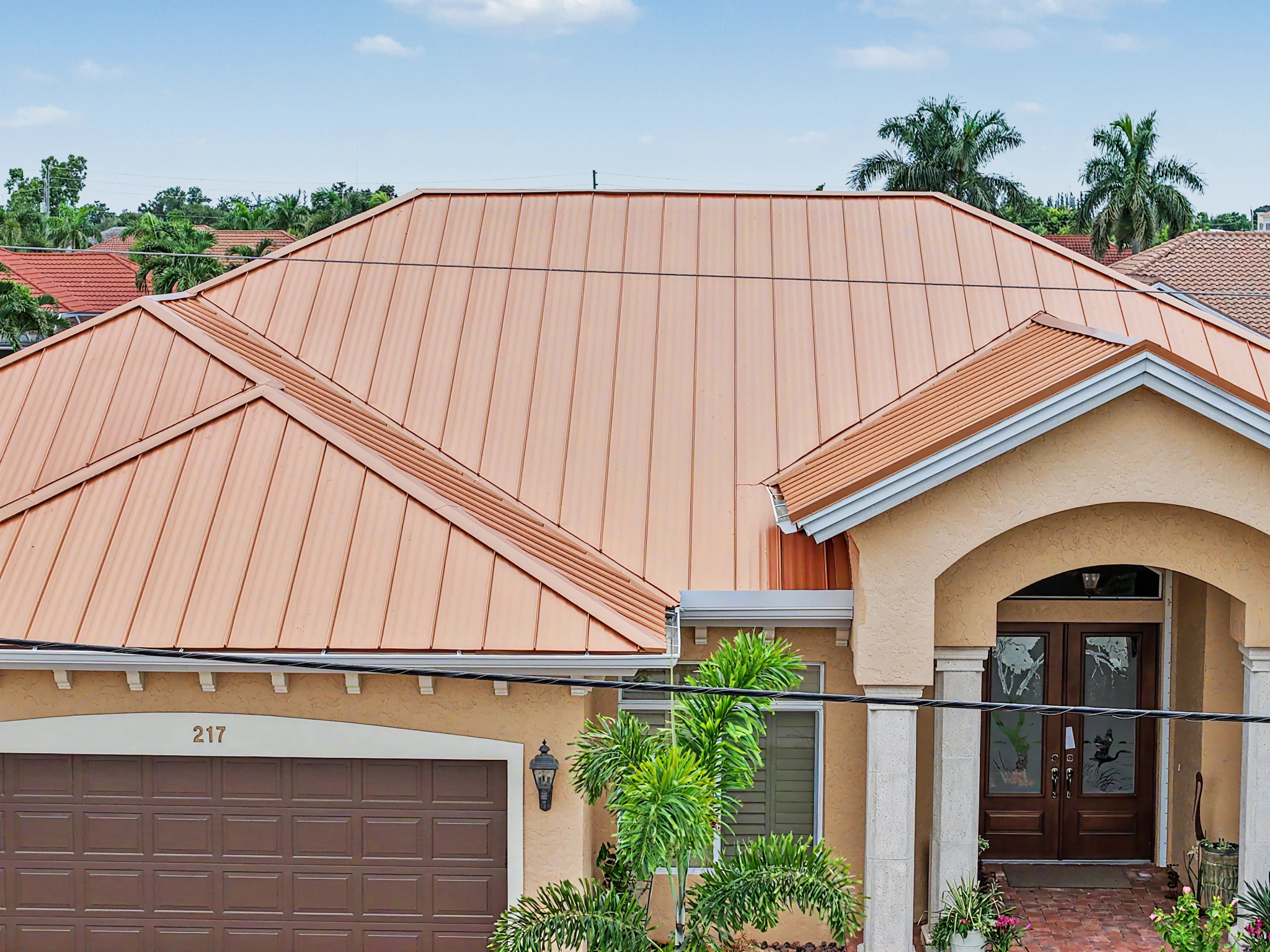 Close front view of a copper-colored standing seam metal roof installed above the garage and arched  