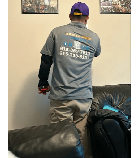 Professional heating and cooling technician providing residential HVAC service inside a customer's home.