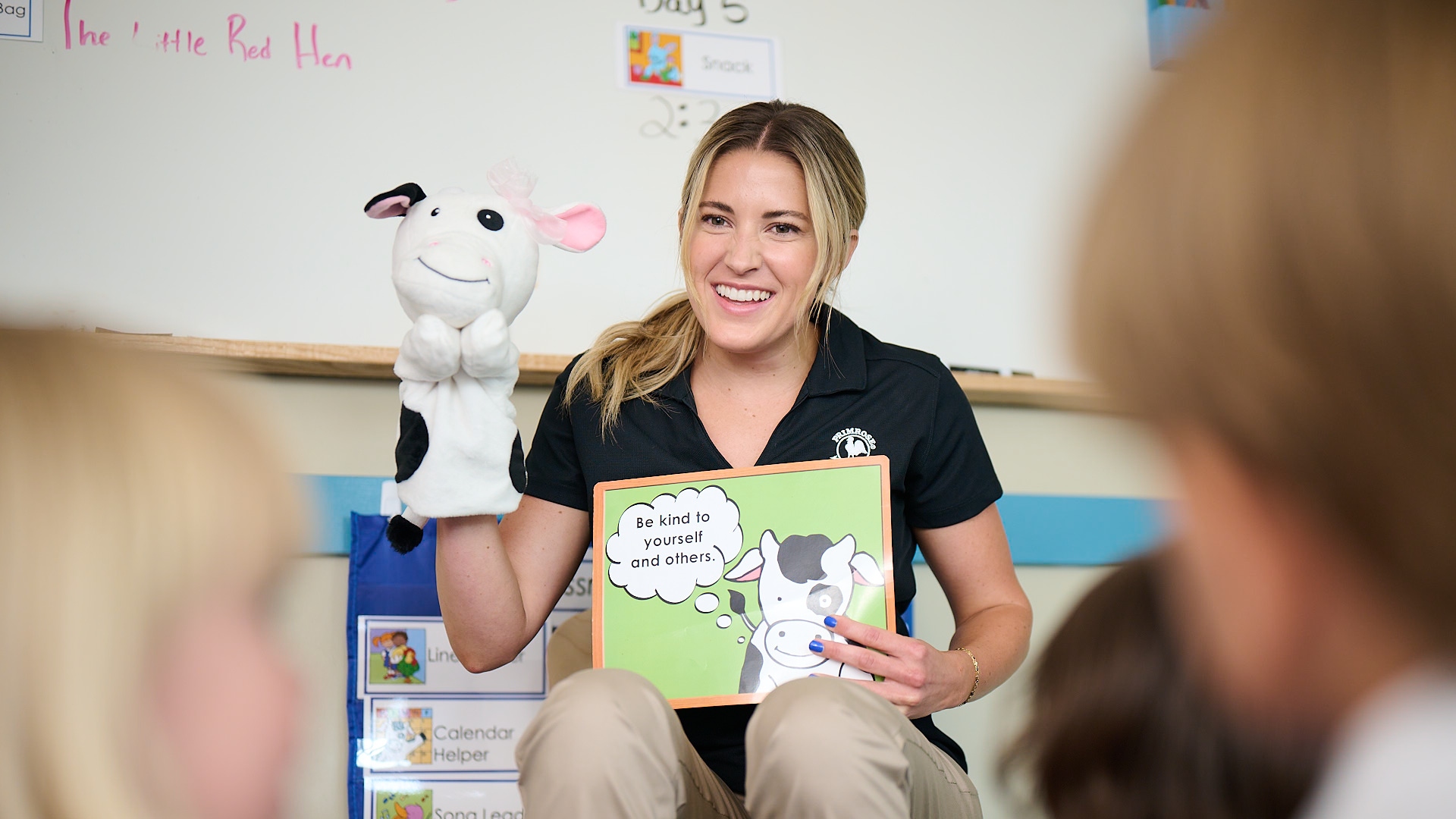 Primrose Schools preschool teacher reading character education book with cow hand puppet to young children
