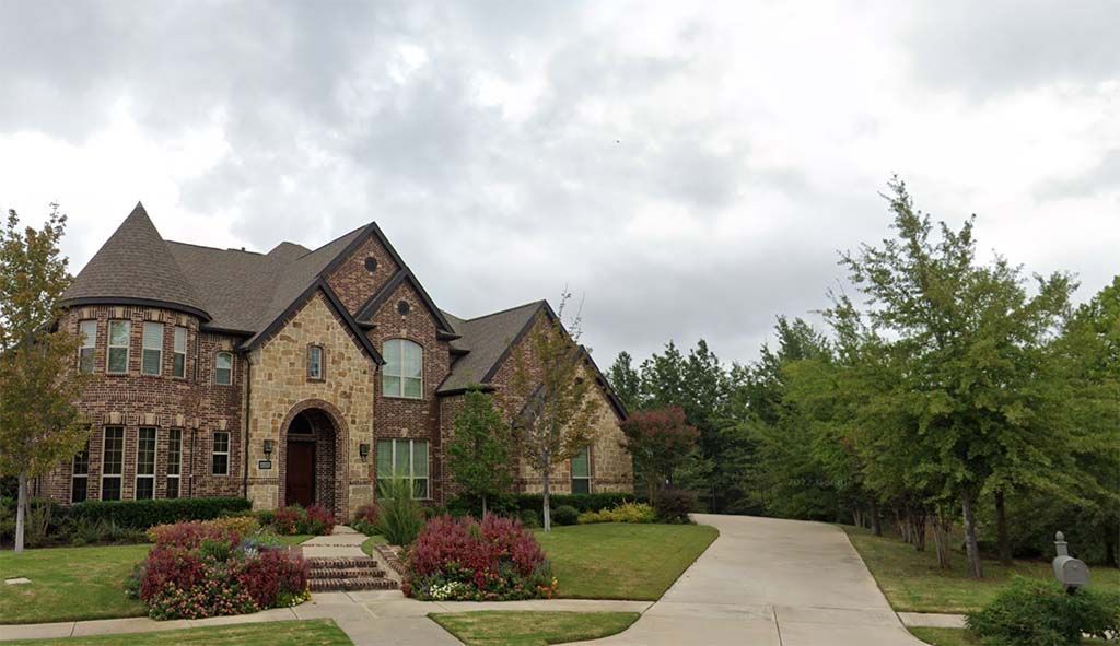 A large custom-built luxury residence features an attractive architectural shingle roof that complements elegant brick and stone exterior finishes while enhancing curb appeal and long-term weather protection.