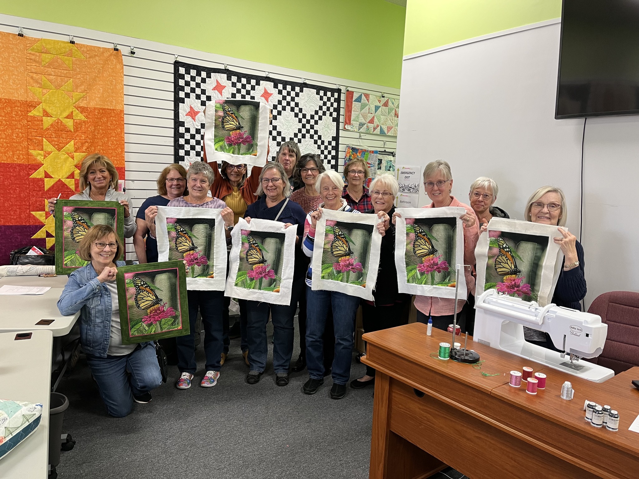 Students proudly display their completed butterfly-themed Decorative Stitch quilt panels after a hands-on quilting class. A creative workshop focused on decorative stitching, embroidery techniques, and quilting skills.
