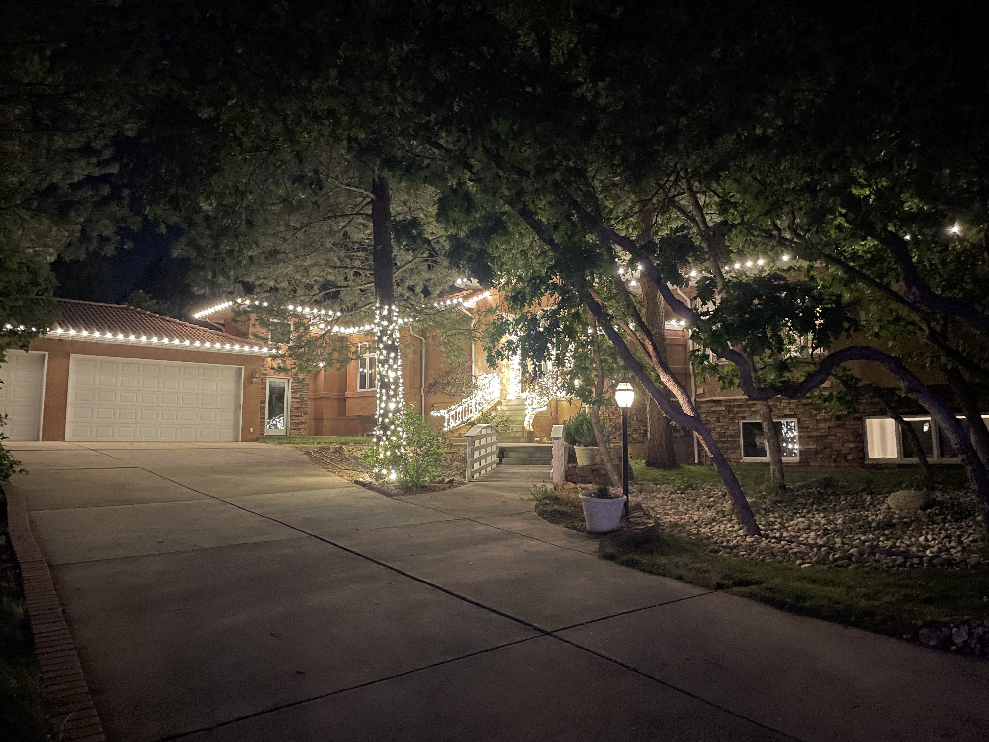 Roofline lights along the garage and main roof, with a wrapped trunk and lamp post lighting the appr 