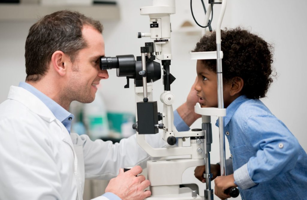 Child receiving an eye exam through a slit lamp