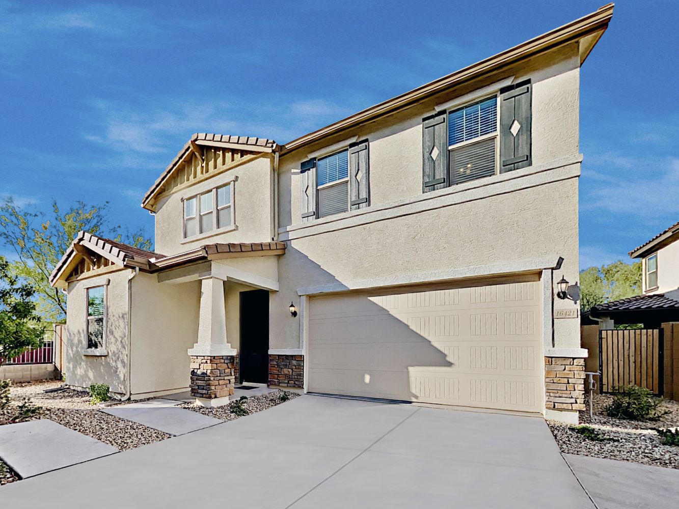 Stunning front of home with a two-car garage and covered porch at Invitation Homes Phoenix.