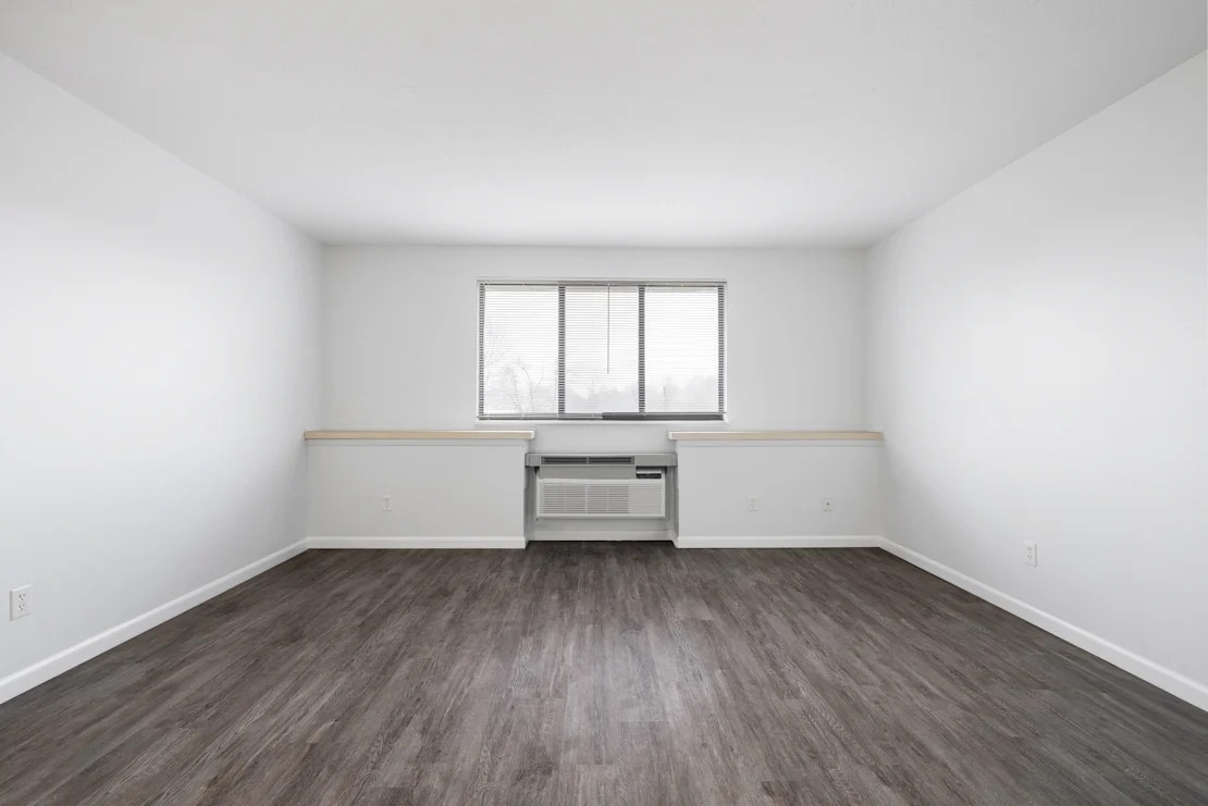 A room with a window and a wooden floor.