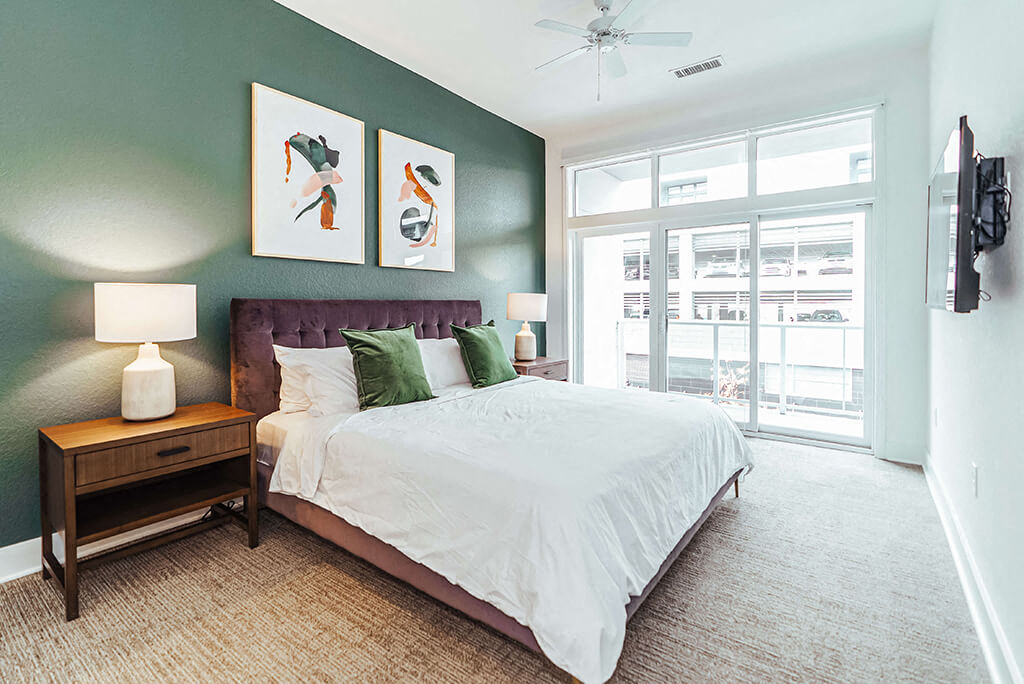 Bedroom with green accent wall and large windows
