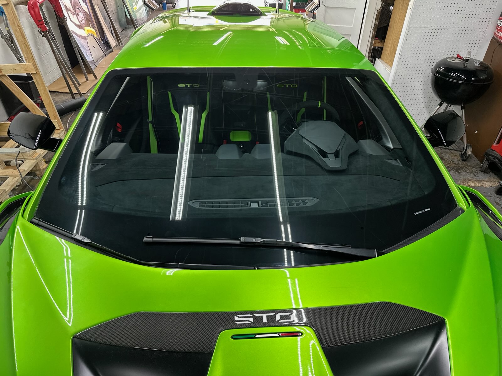 A bright green Lamborghini STO is shown inside the shop with a clear windshield installed. The image demonstrates Space Auto Glass service on specialty and high-performance vehicles.