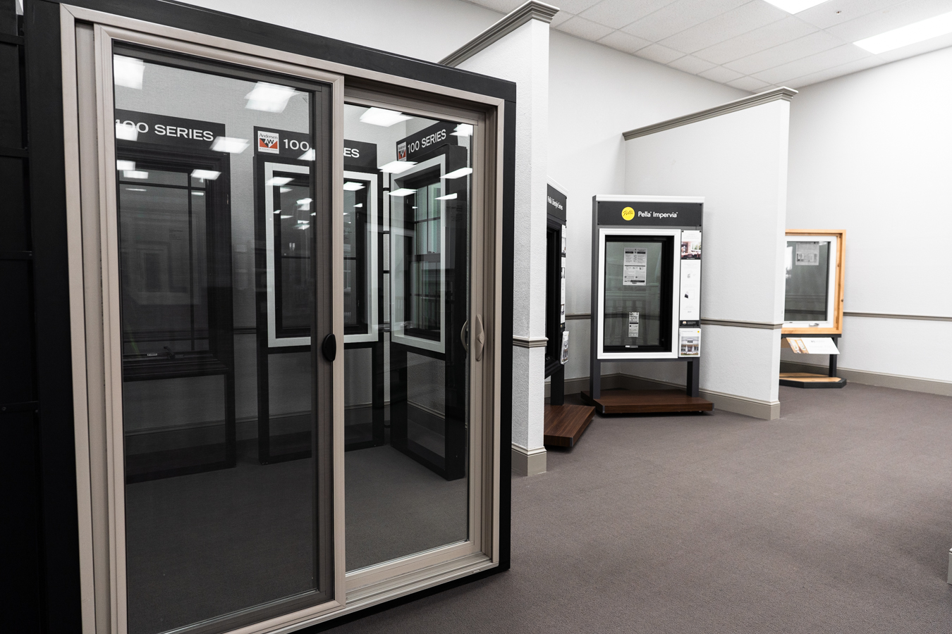 Builders FirstSource showroom displays sliding doors and windows, featuring Andersen 100 Series and Pella Impervia models.