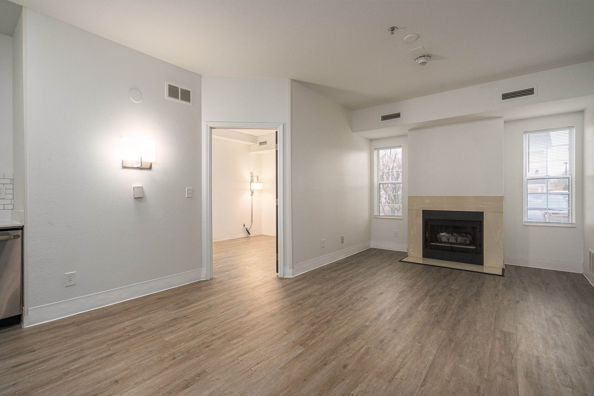 an empty living room with a fireplace and wood flooring at AVIA Lofts on Victors Way in Ann Arbor, MI