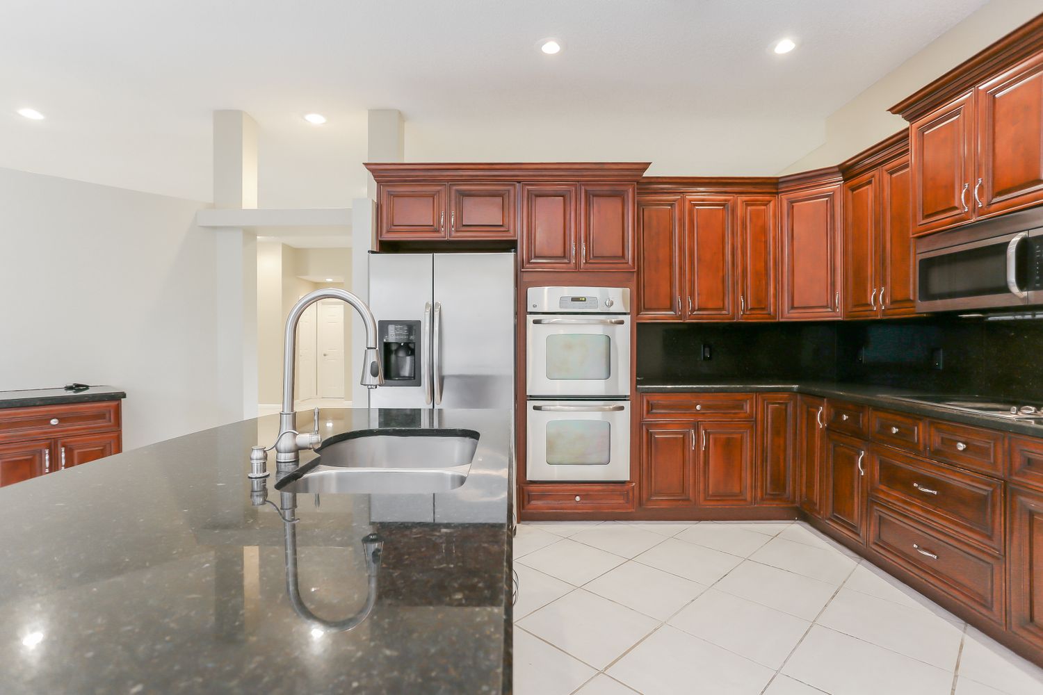 Modern kitchen with granite and stainless steel appliances in an Invitation Homes property in South Florida.