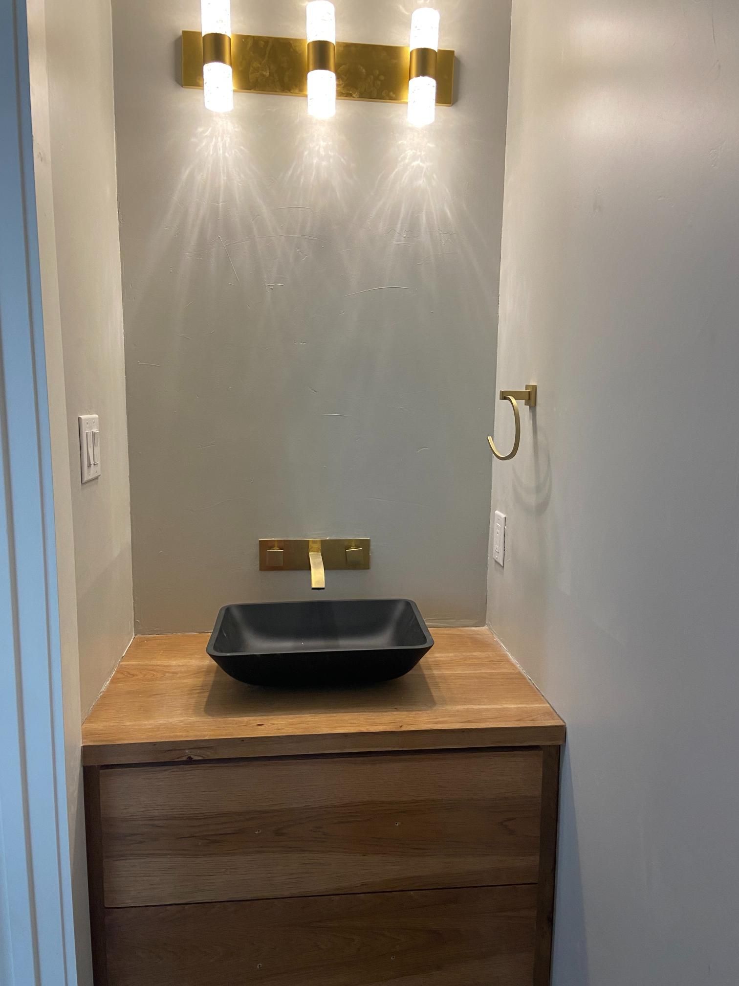 Bathroom remodeling project featuring a custom wooden vanity, black vessel sink, gold faucet, matchi 