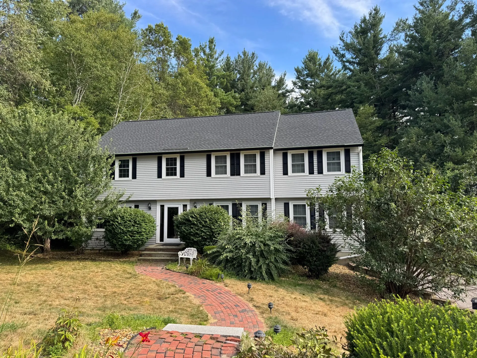 Large residential property surrounded by landscaping and mature trees. Exterior features include roo 