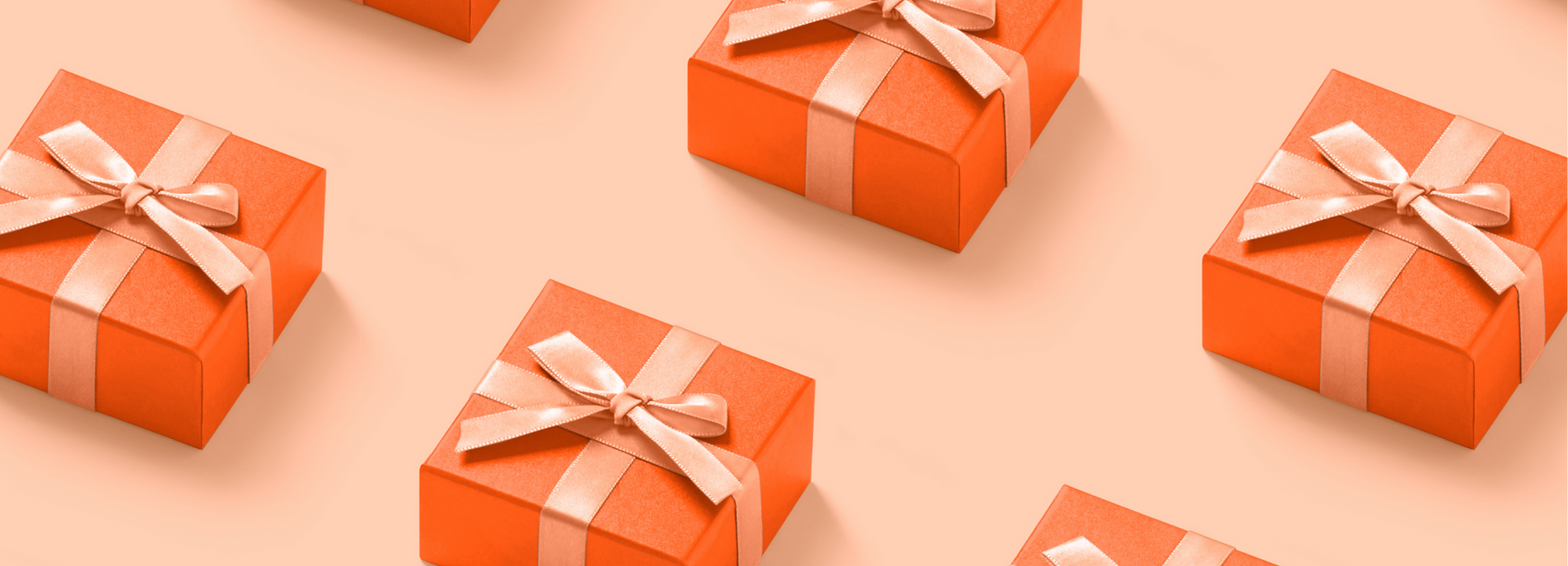 A collection of brightly colored orange gift boxes with satin ribbons are arranged in a repeating pattern on a soft peach background, casting subtle shadows. The boxes are seen from a slightly elevated angle, creating a sense of depth and visual interest.