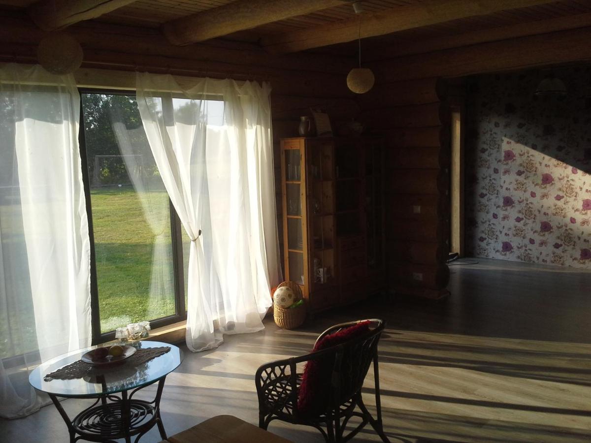Gaiša un mājīga guļamistaba viesu namā 'Palmas' ar komfortablu gultu, koka detaļām un logu ar skatu uz dabu.