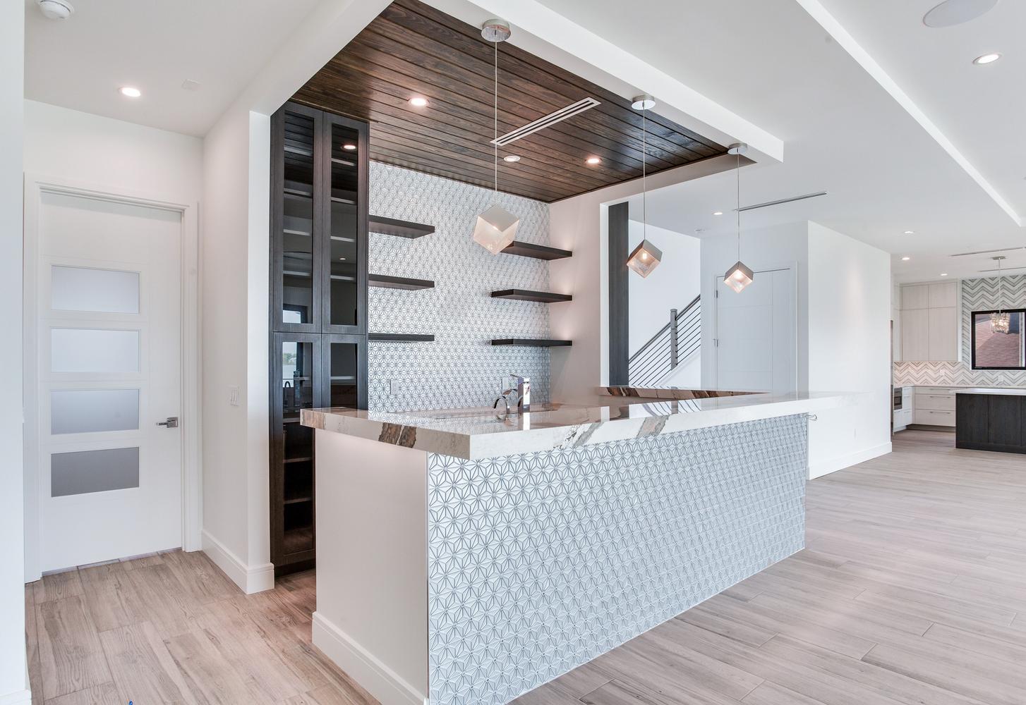 Contemporary custom kitchen with a waterfall island, sleek cabinetry, built-in shelving, pendant lighting, and high-end interior finishes.