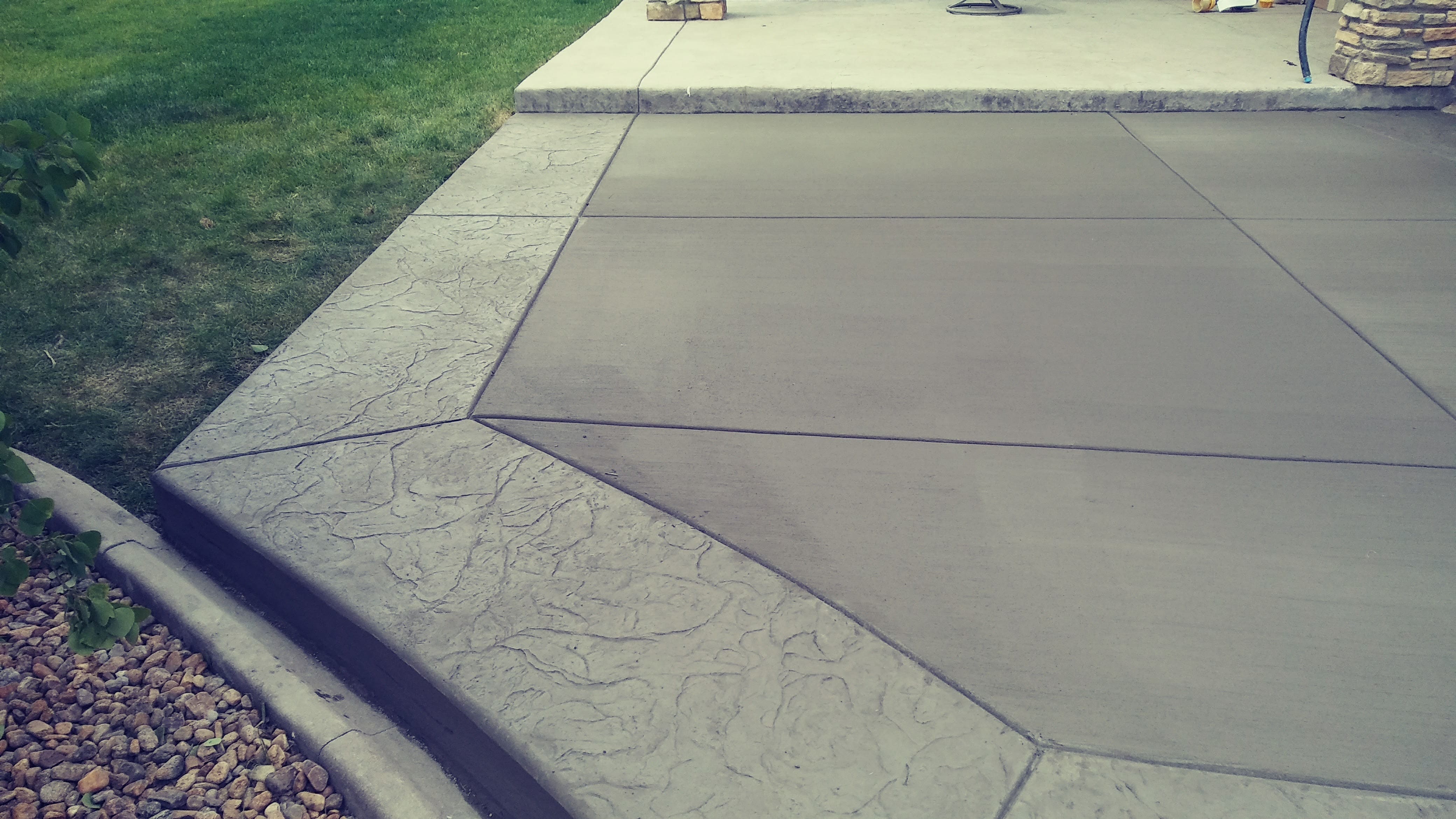 Decorative concrete patio featuring a stamped stone-textured border surrounding a smooth central surface for a distinctive outdoor living area.