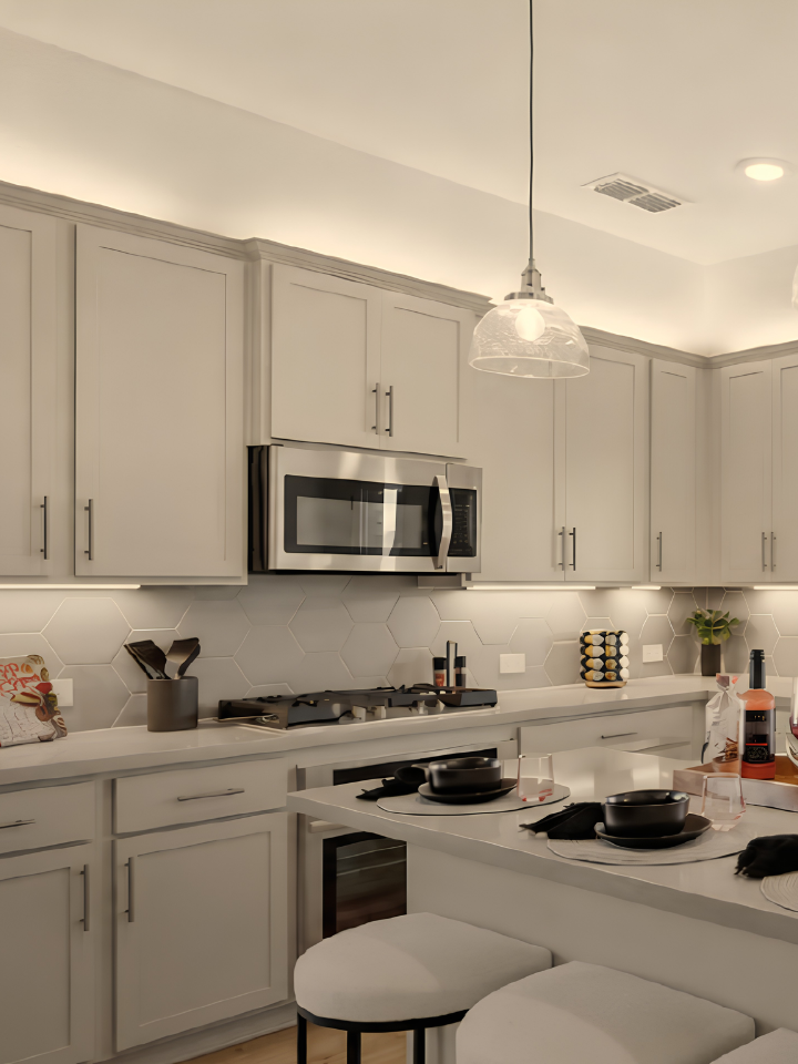 White shaker cabinets with a spacious kitchen island, decorative hardware, patterned tile backsplash, and stainless steel appliances in a bright, modern kitchen design.