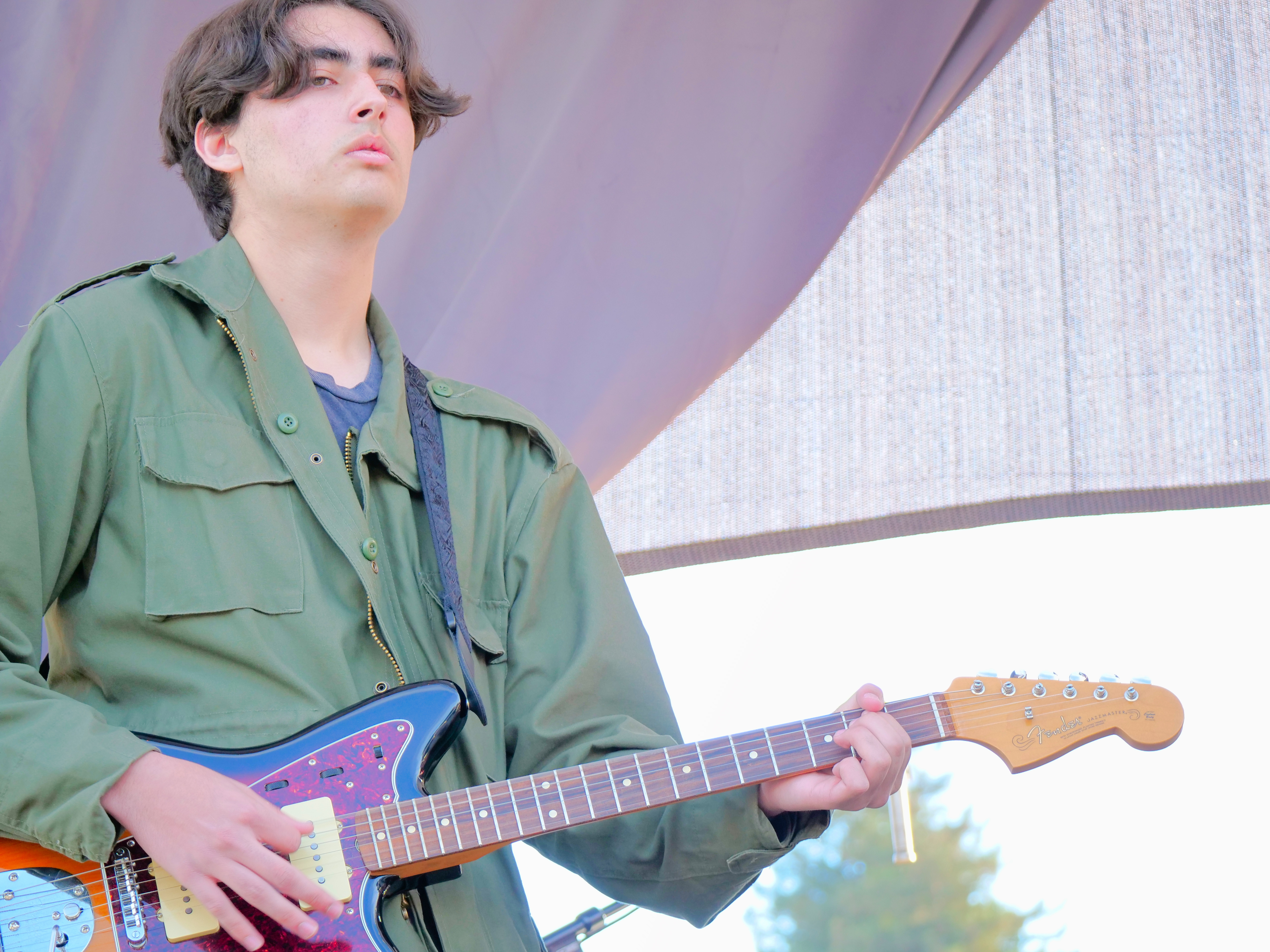 Student guitarist performing on stage as part of a live band music program.