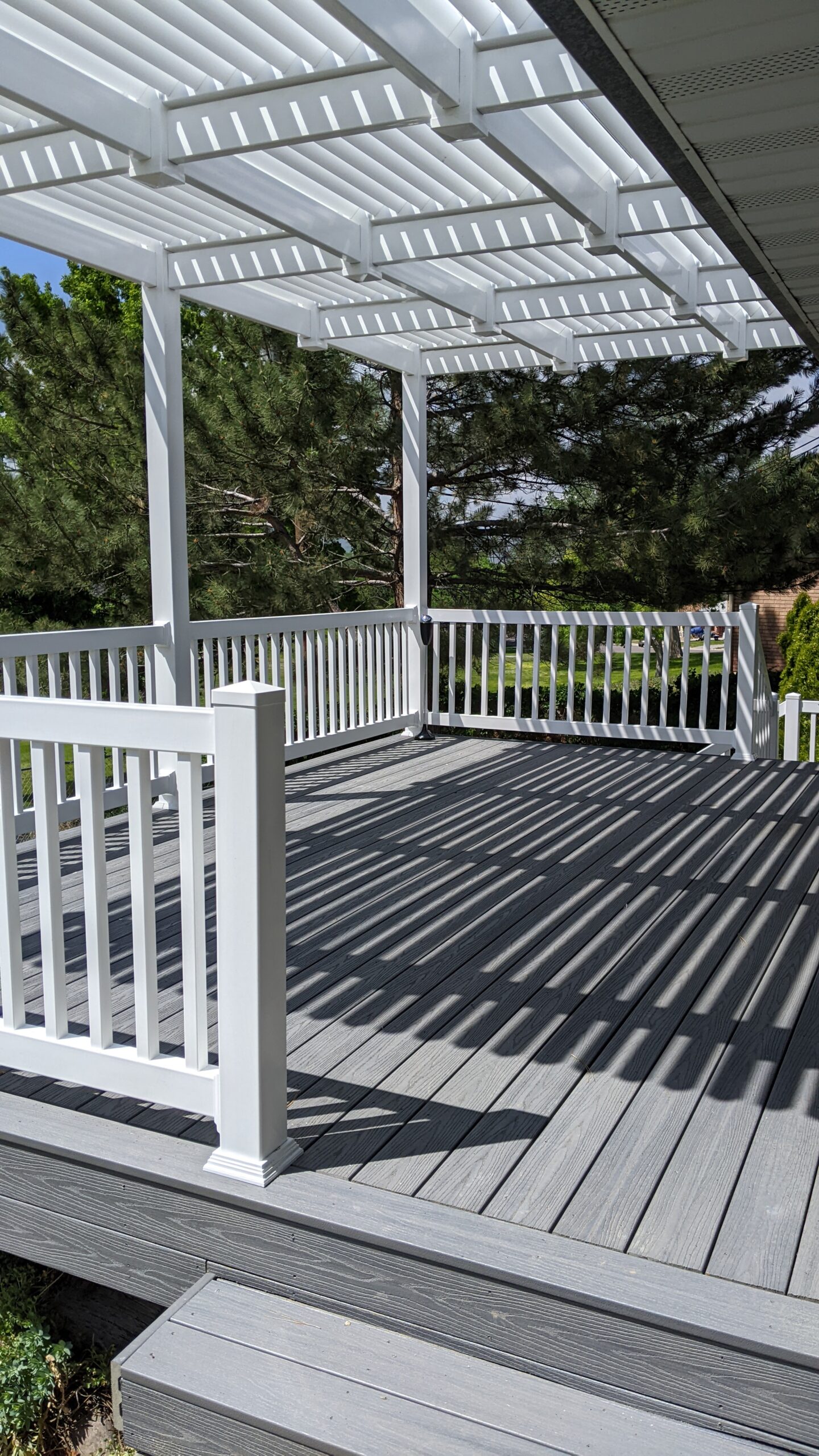 Expand your outdoor living possibilities with this custom composite deck and pergola combination by DeckPro LLC, which combines rustic elements with modern materials. We installed low-maintenance grey composite decking and paired it with a unique louvered pergola system featuring natural wood posts. For the ultimate in functional design, this louvered roof offers customizable shade, creating a cozy and inviting retreat.