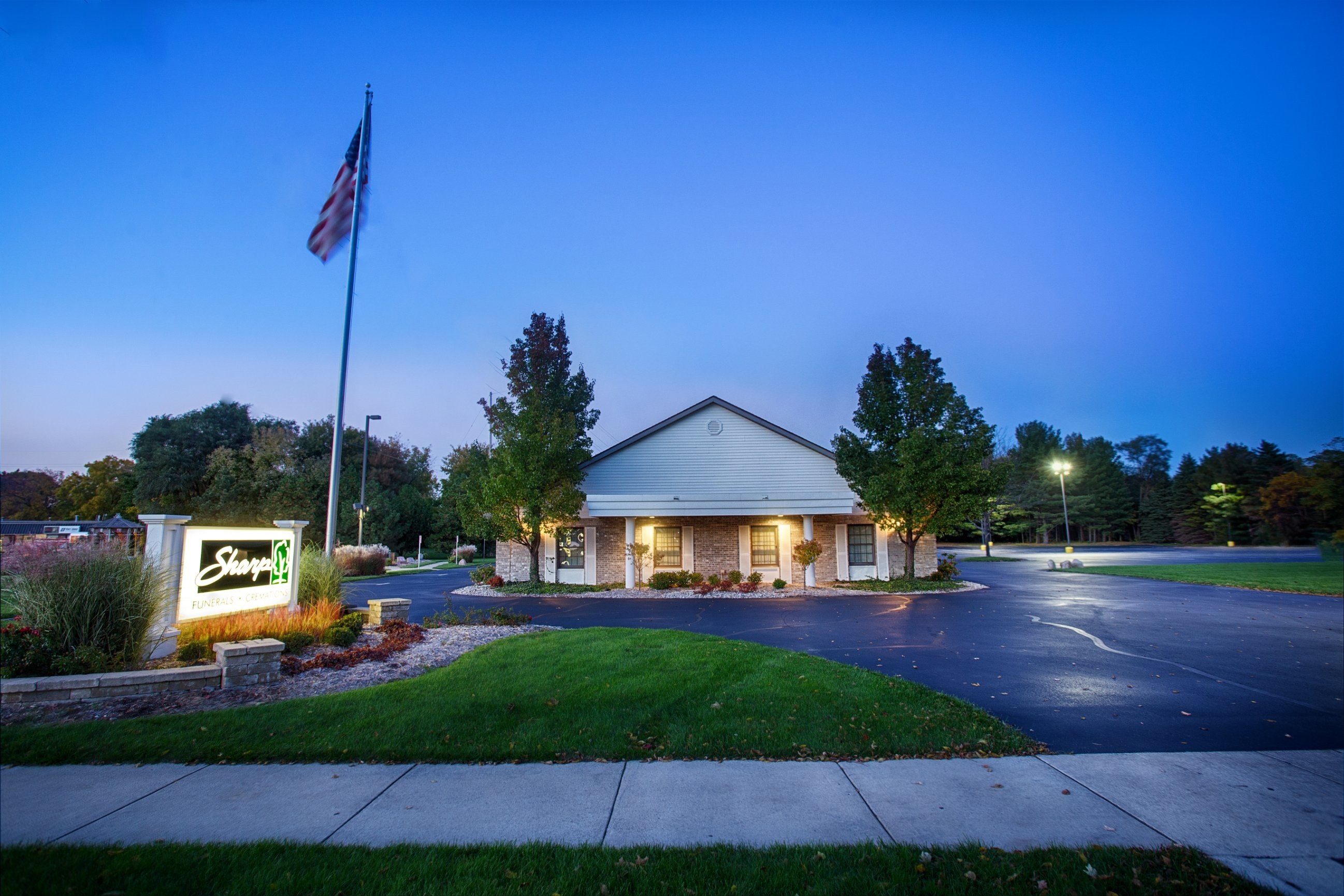 The Fenton Chapel at dusk, with the Sharp sign lit beside the drive on W Silver Lake Rd