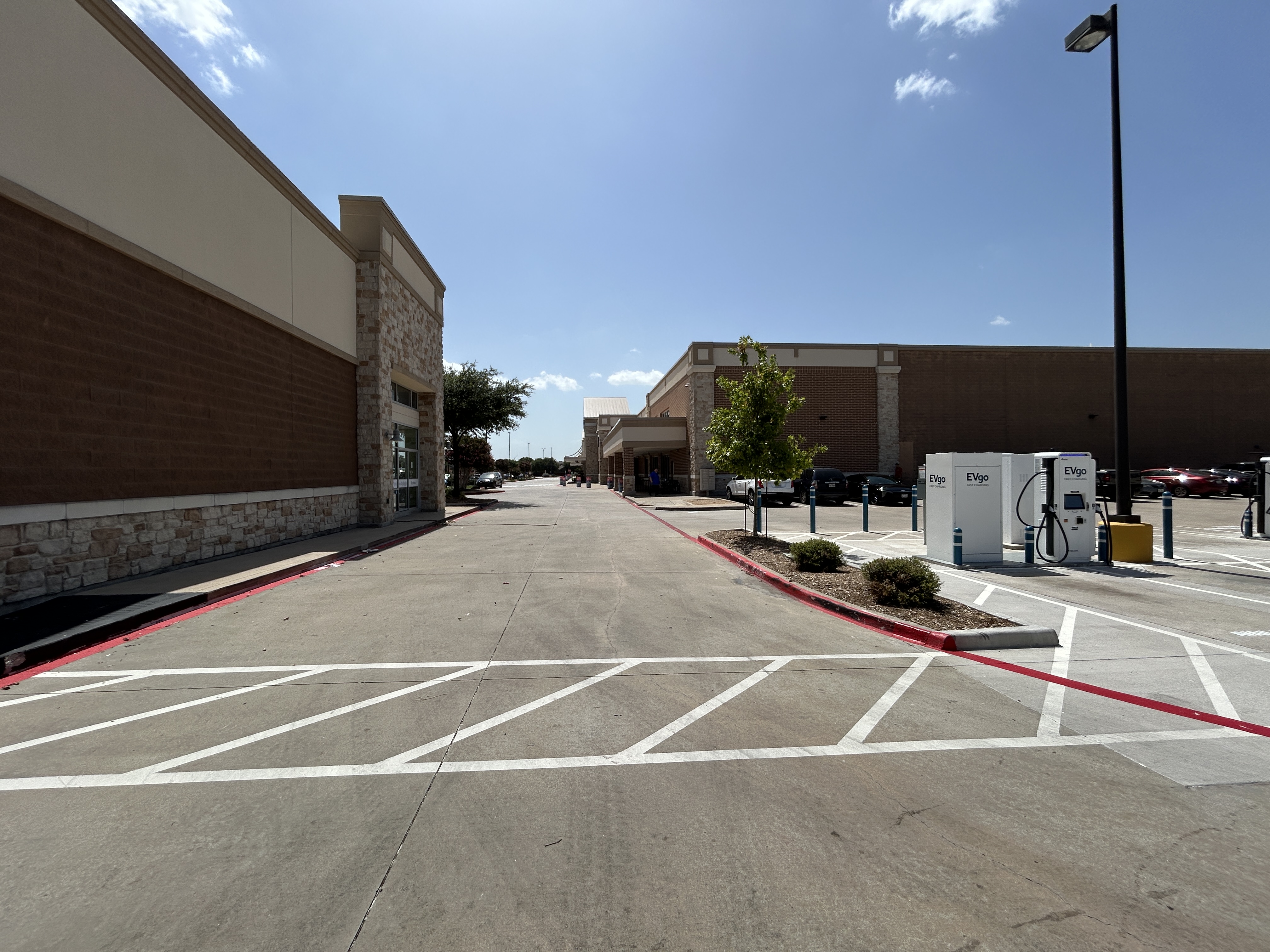 Several EVgo fast charging units installed in marked parking spaces at a public charging station, wi 