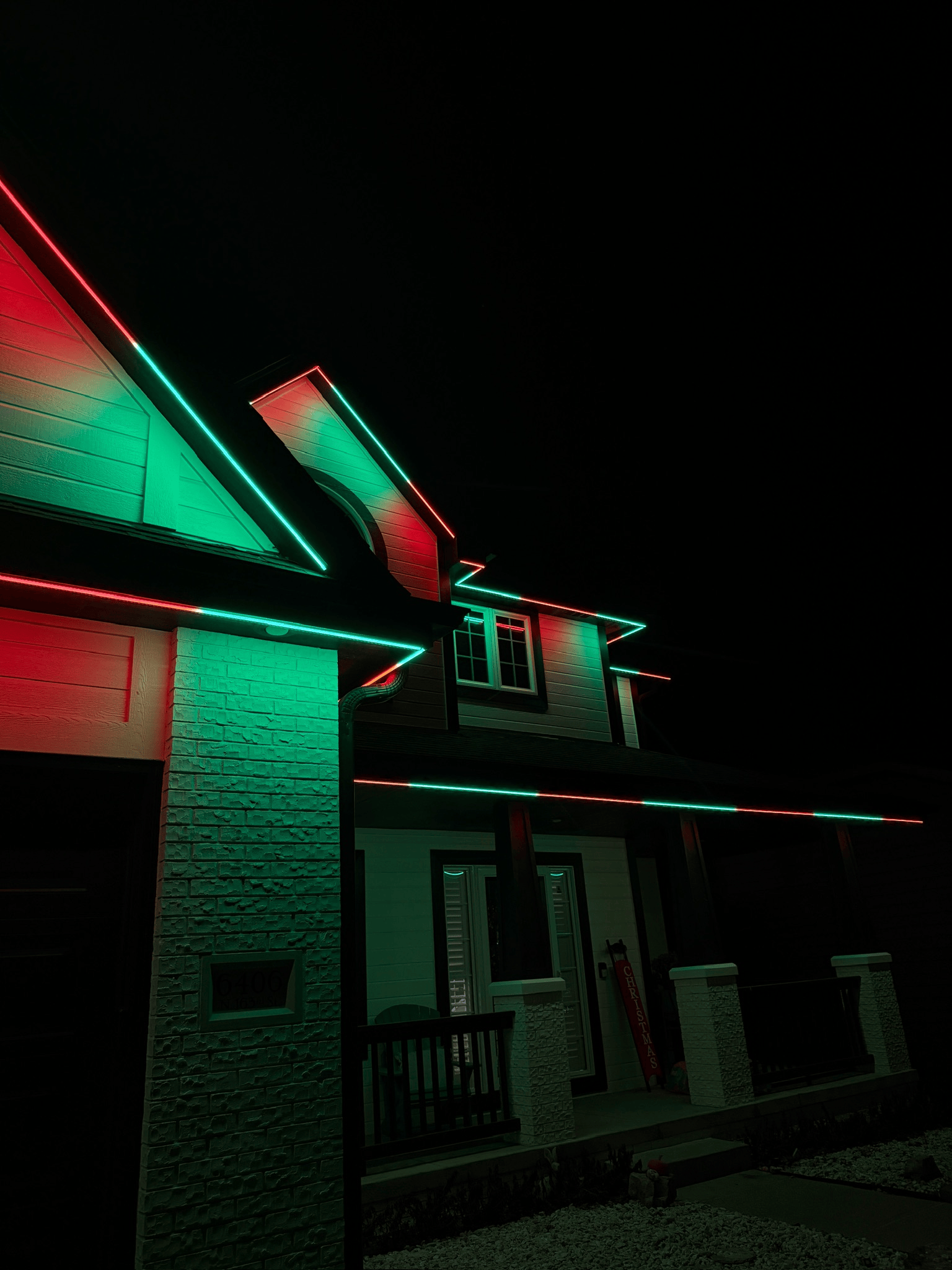 Red and green roofline lighting creating a festive color-changing effect along the exterior of a home.