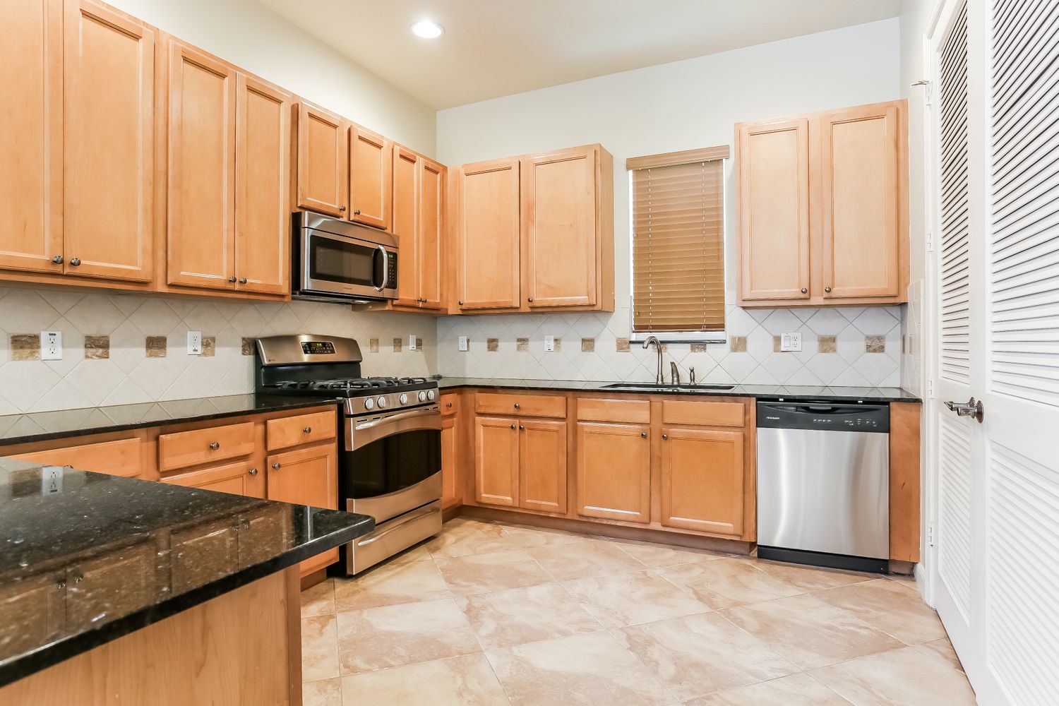 Spacious kitchen with stainless steel appliances and granite countertops at Invitation Homes South Florida.