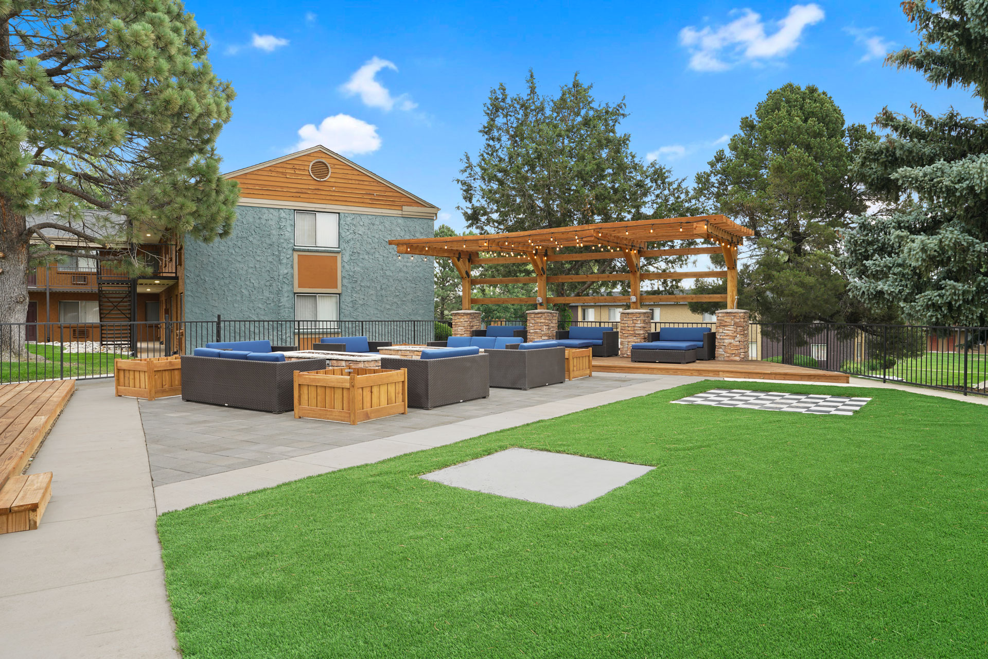 A large building with a wooden pergola and a green lawn in front.