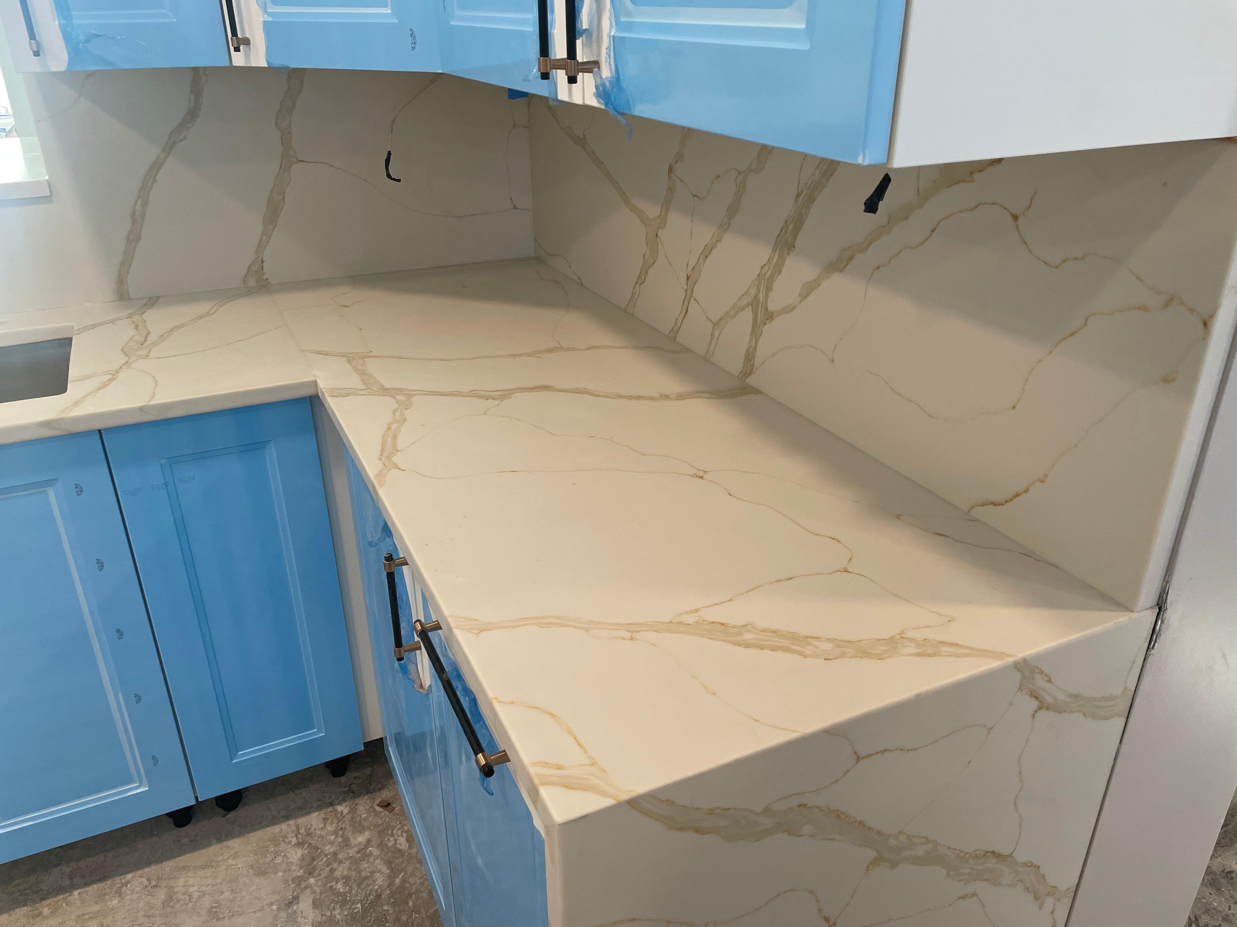 Updated kitchen with white cabinets and white marble countertops.