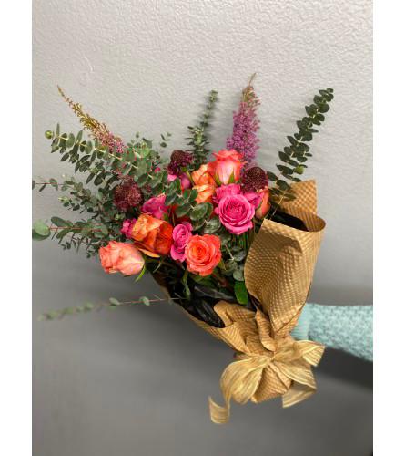 Handwrapped bouquet with roses, spray roses, scabiosa scoops and eucalyptus greenery.