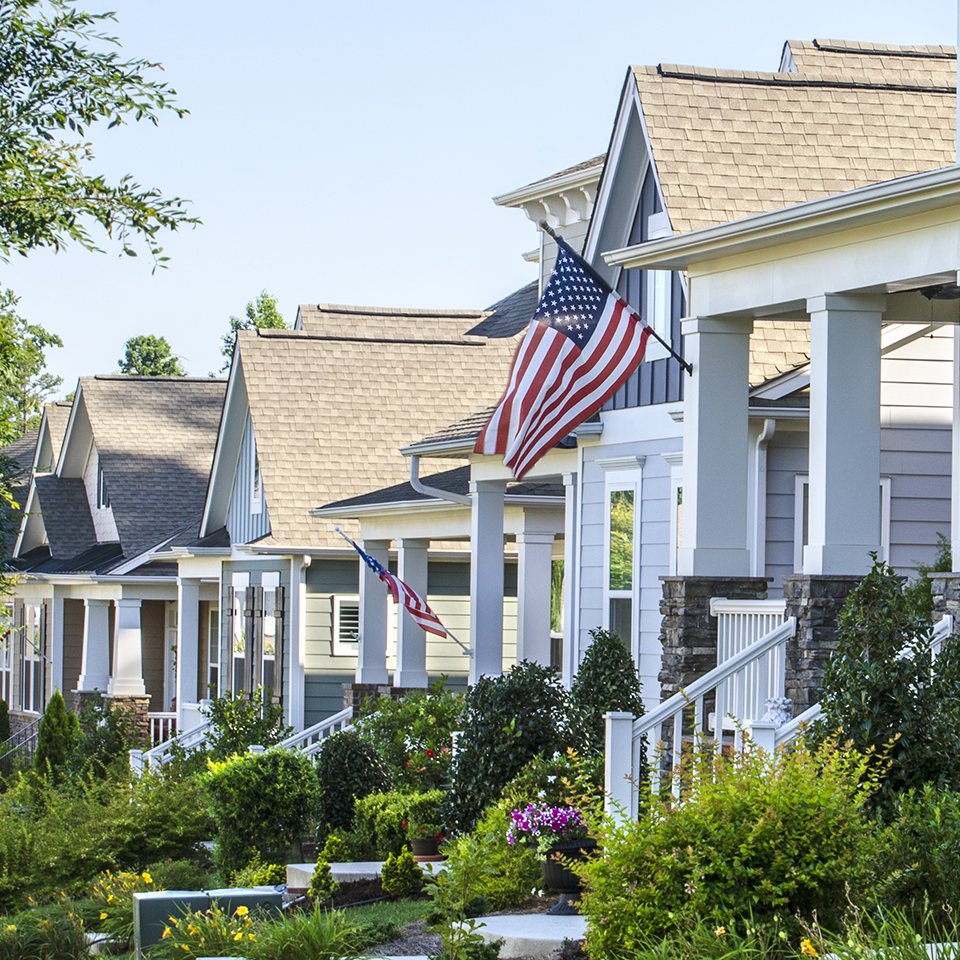 A row of houses with one hanging an American flag.